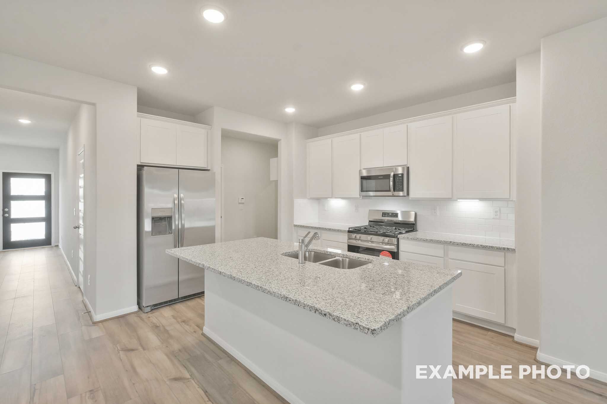 Gourmet kitchen in The Brazos by Davidson Homes featuring granite island, white cabinetry, and stainless steel appliances