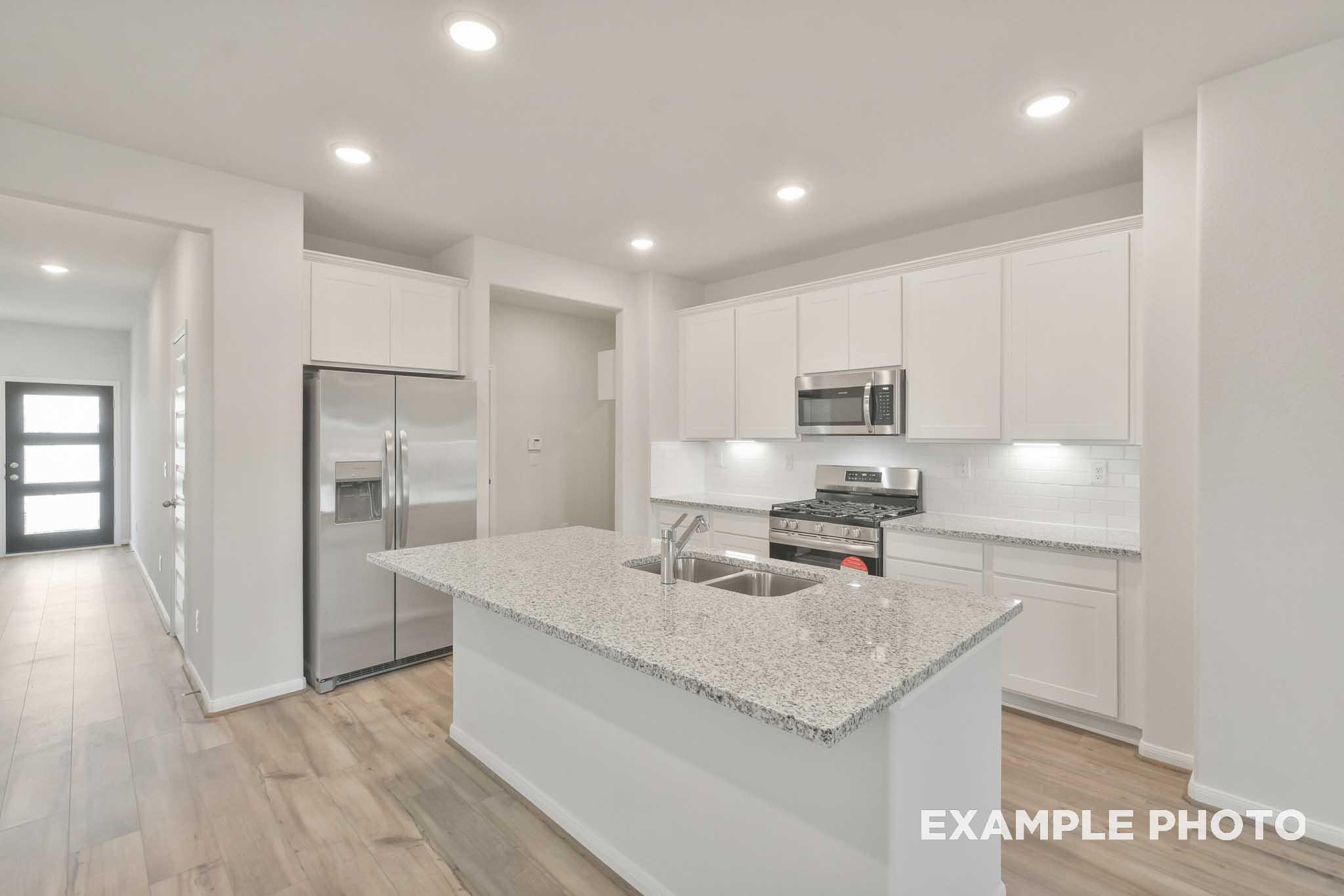 Gourmet kitchen in The Brazos by Davidson Homes featuring granite island, white cabinetry, and stainless steel appliances