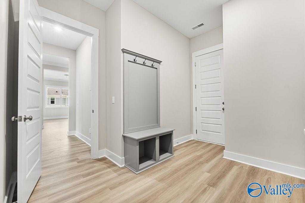 Entryway with built-in gray bench and coat hooks in 5-bedroom The Oxford home by Evermore Homes, Owens Cross Roads, Alabama