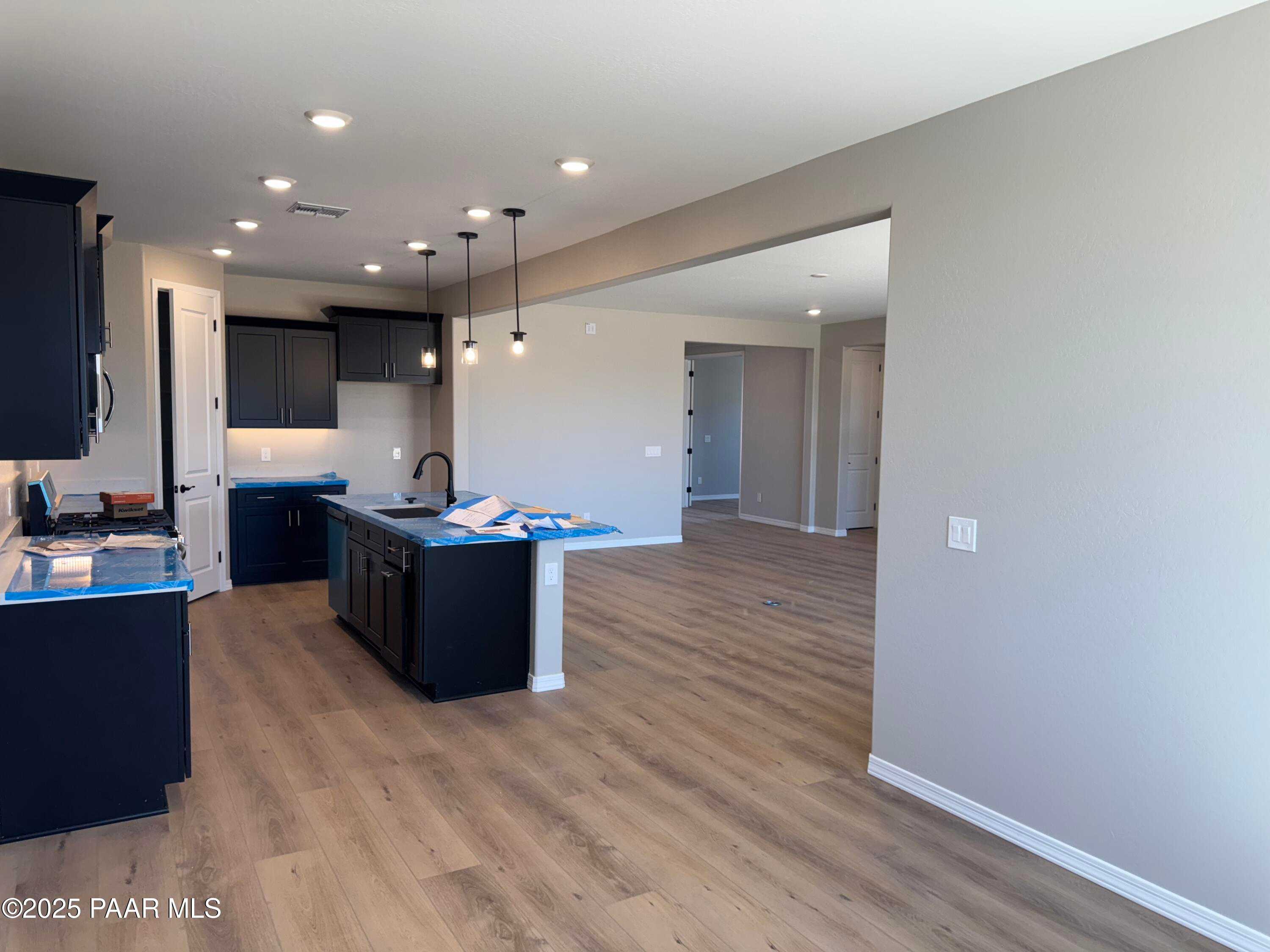 Modern kitchen with dark cabinetry, large island, farmhouse sink, and open layout to living area in The Sheridan II B, Prescott, AZ