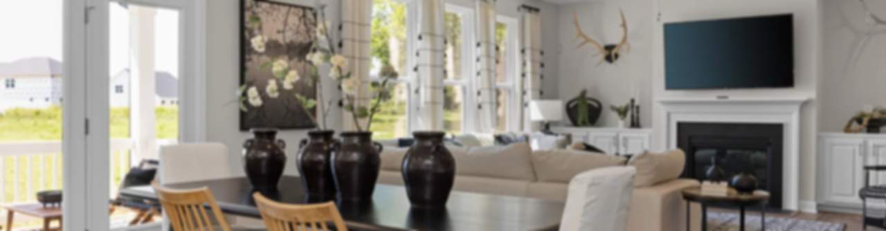 Spacious open-plan living dining room in modern new Durham home with fireplace, large windows, and wooden table