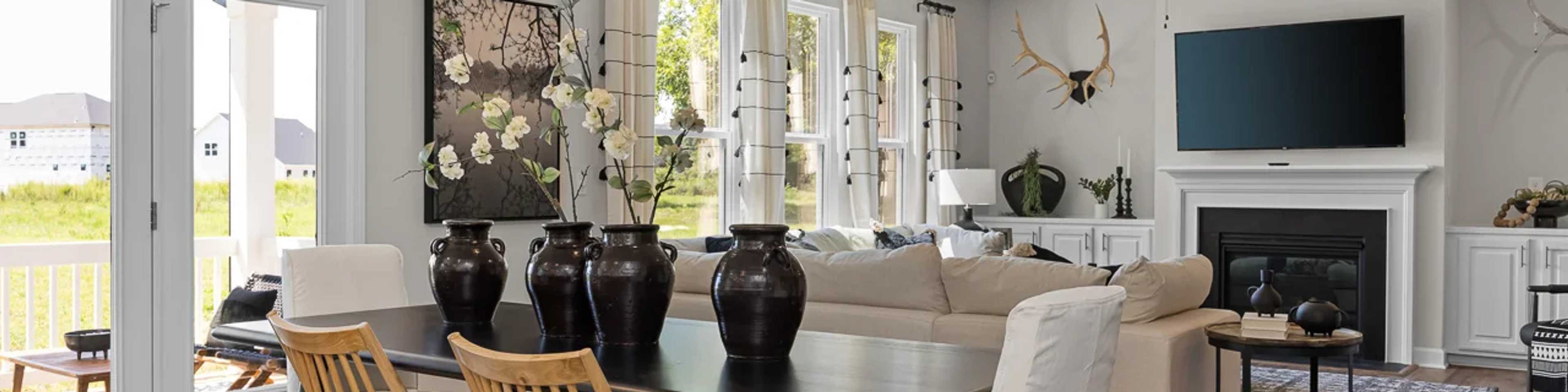 Spacious open-plan living dining room in modern new Durham home with fireplace, large windows, and wooden table