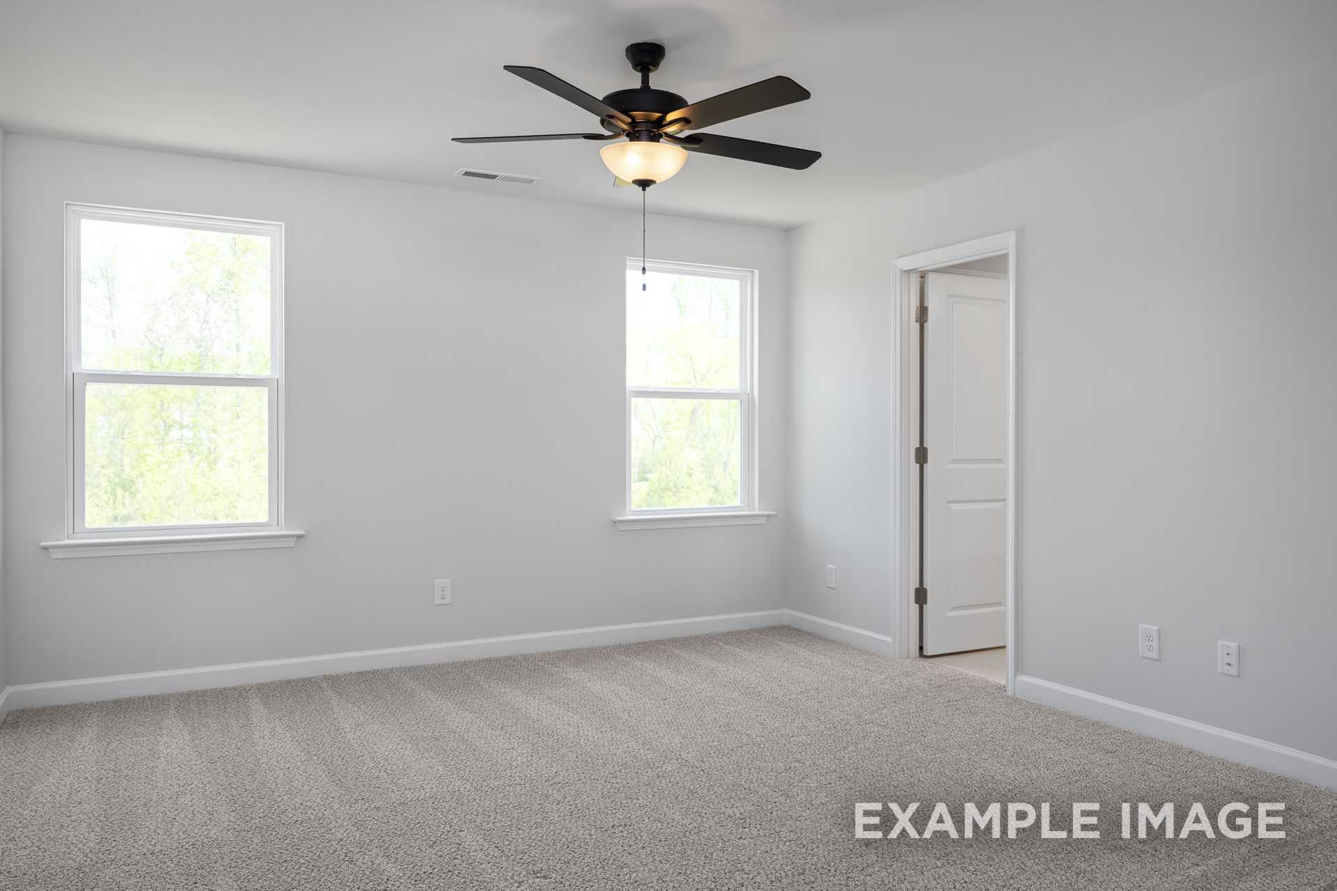 Bright upstairs bedroom in The Grace C with ceiling fan, double windows, neutral carpet, and open door