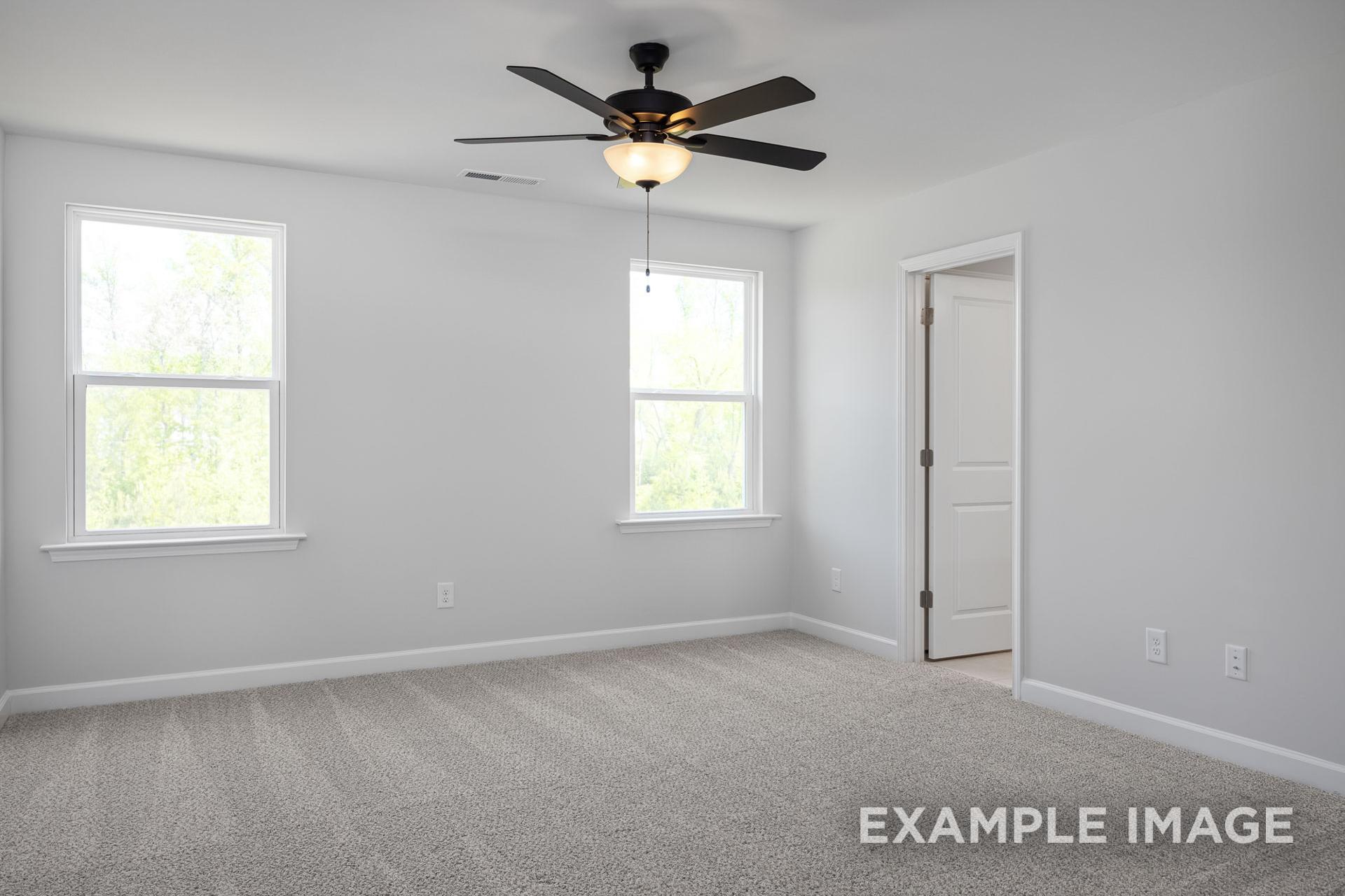 Bright upstairs bedroom in The Grace C with ceiling fan, double windows, neutral carpet, and open door