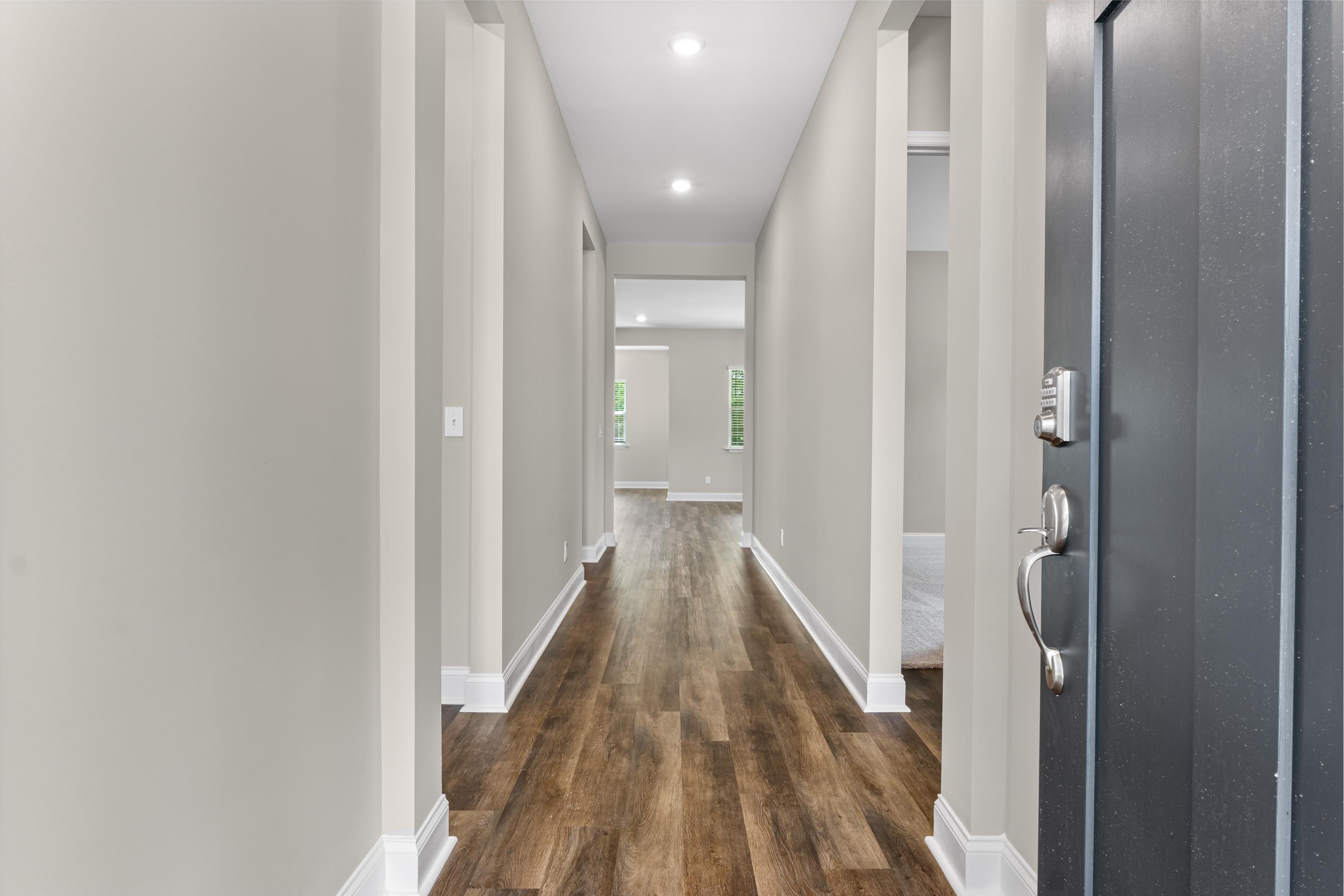 Spacious entryway in The Arcadia B home with light gray walls, hardwood floors, and modern black front door