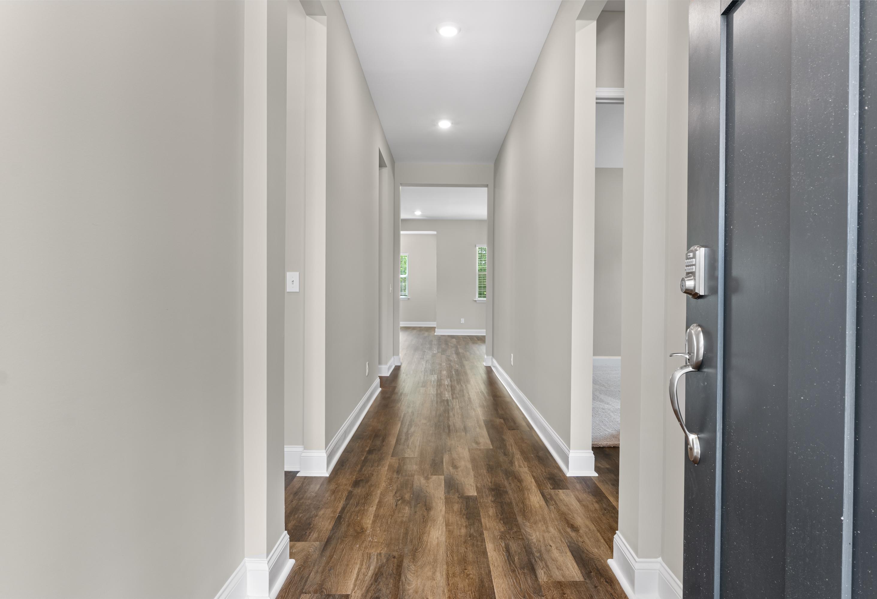 Spacious entry hallway in The Arcadia E home by Evermore Homes, light gray walls, hardwood floors, modern black front door