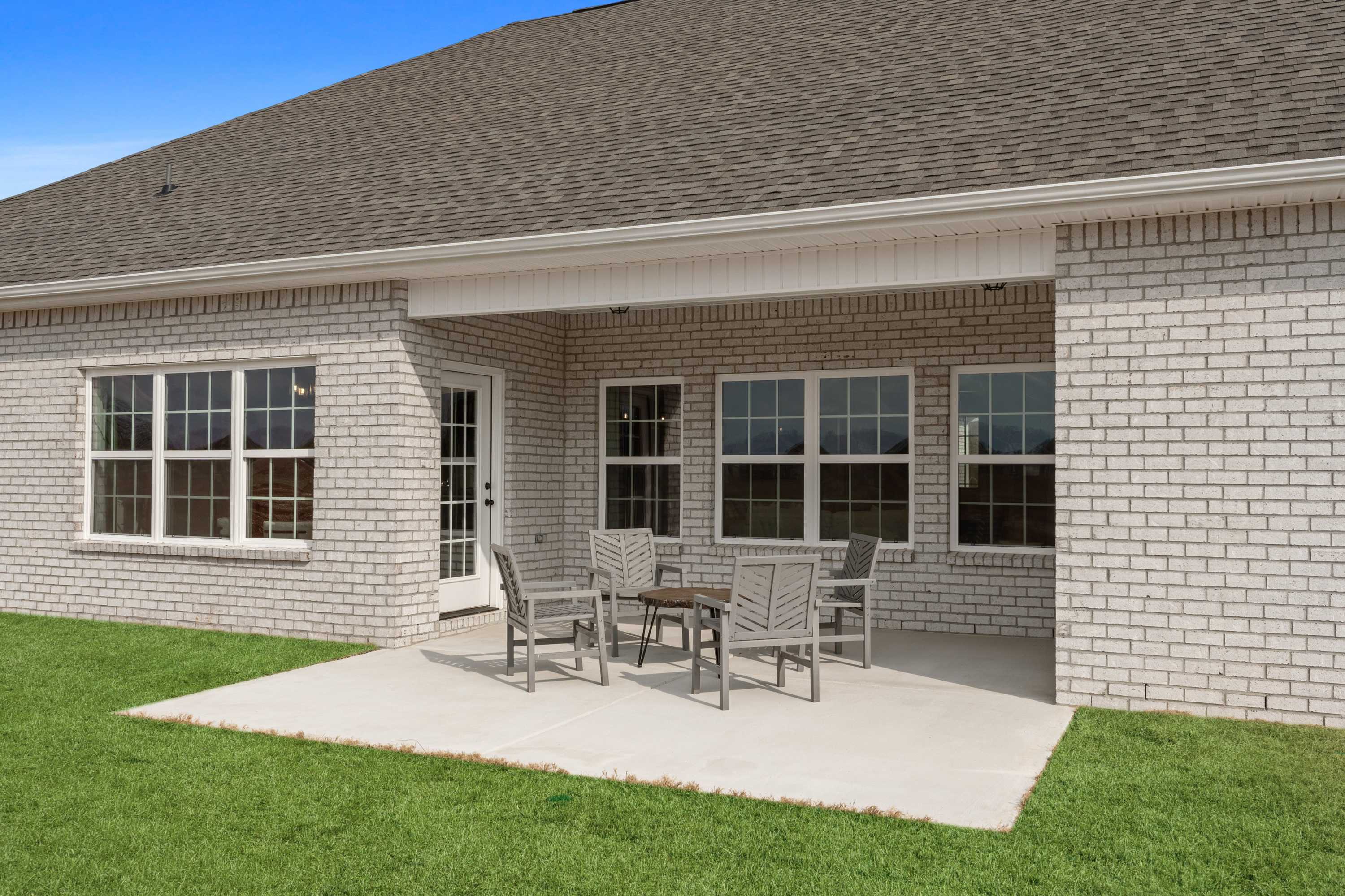 Covered brick patio with outdoor seating and lush lawn at Briercreek in Meridianville Alabama by Davidson Homes