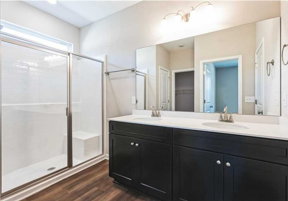 Modern master bathroom with frameless glass shower and double black vanity in Evermore Homes The Aurora A, Cusseta, Alabama