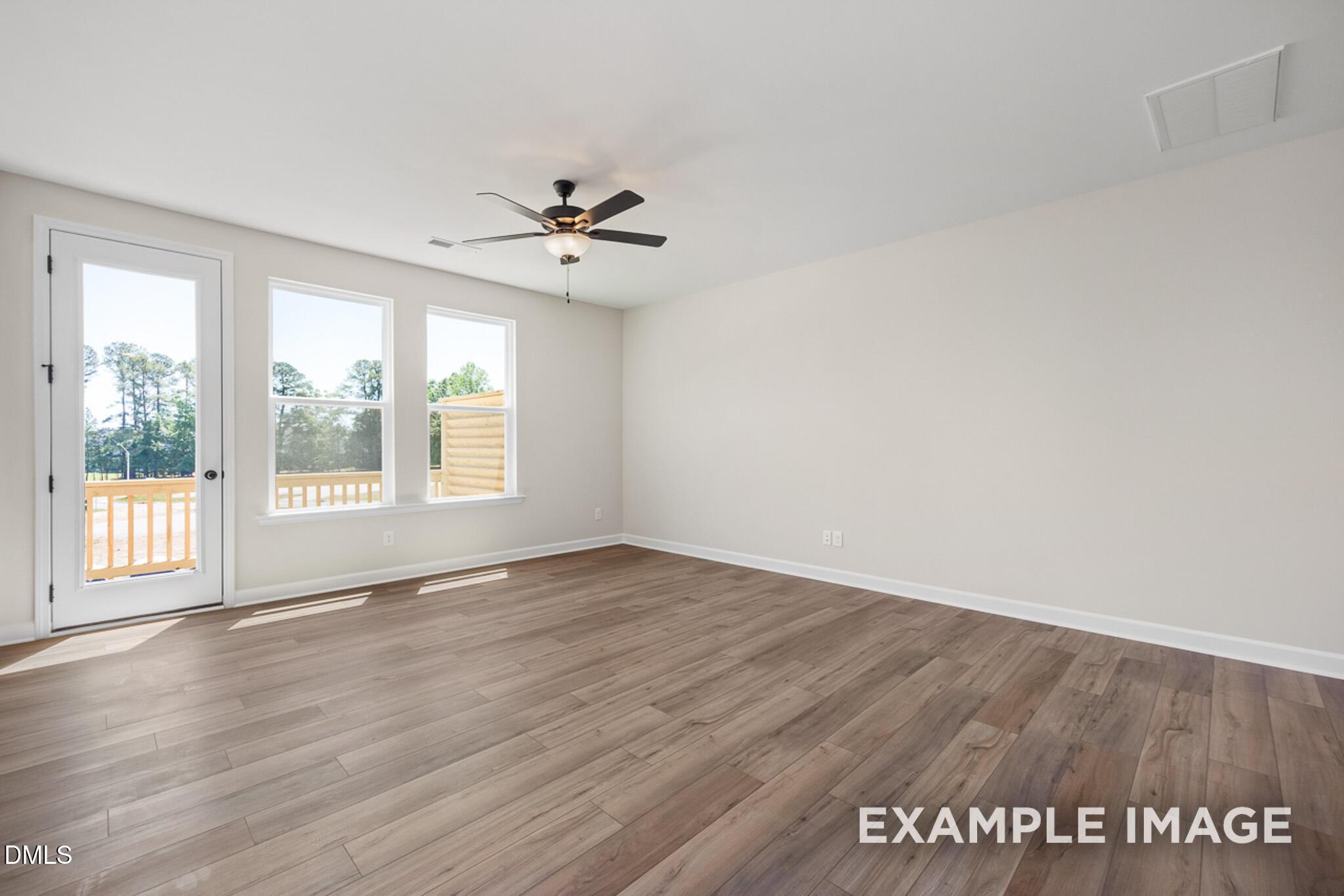 Bright living area with wood-style flooring and deck access in The Mitchell floor plan at Camden Park, Knightdale, NC.