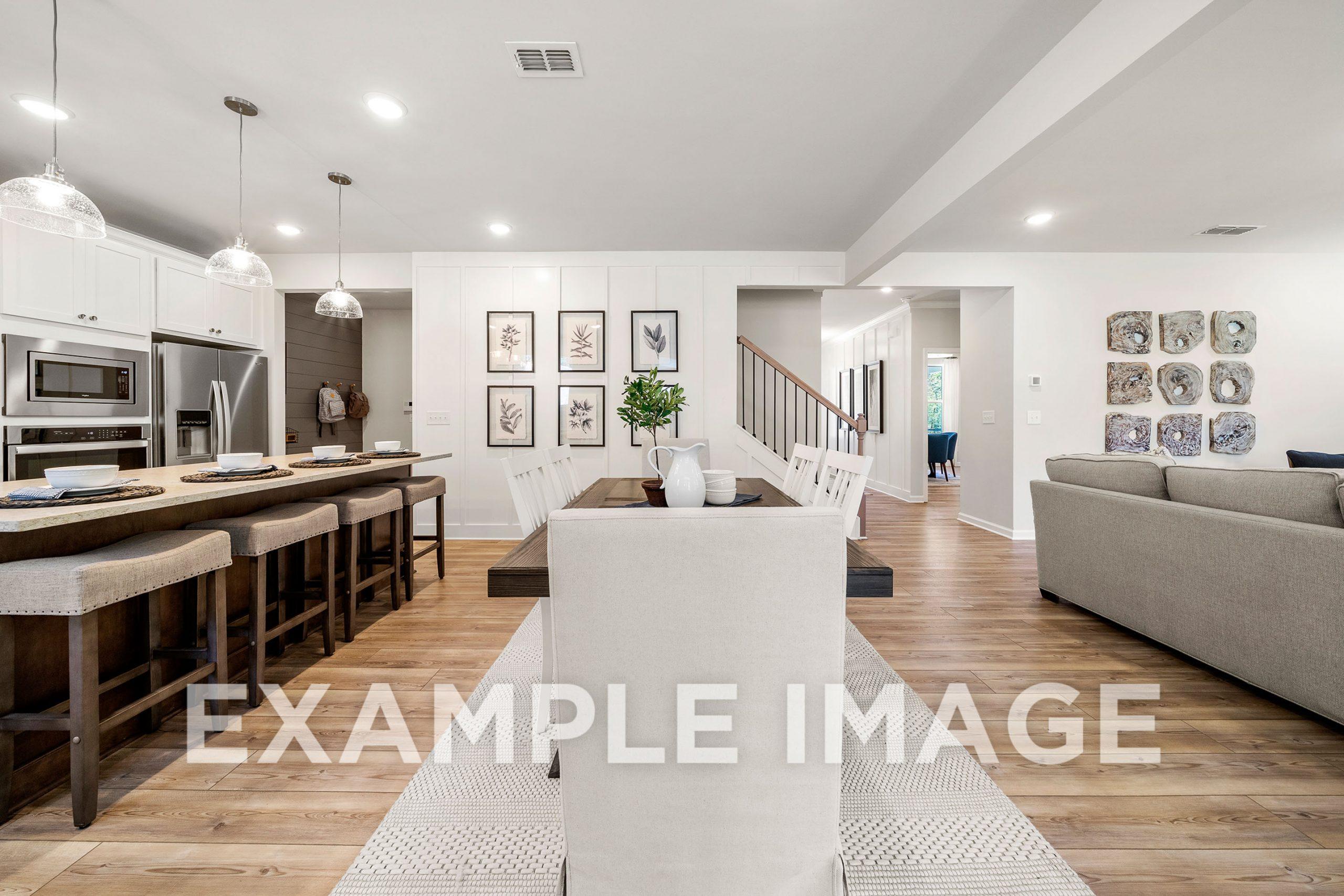 Spacious open-concept kitchen and dining in The Hickory B with white cabinetry, large island, bar stools, hardwood floors, and adjacent living area