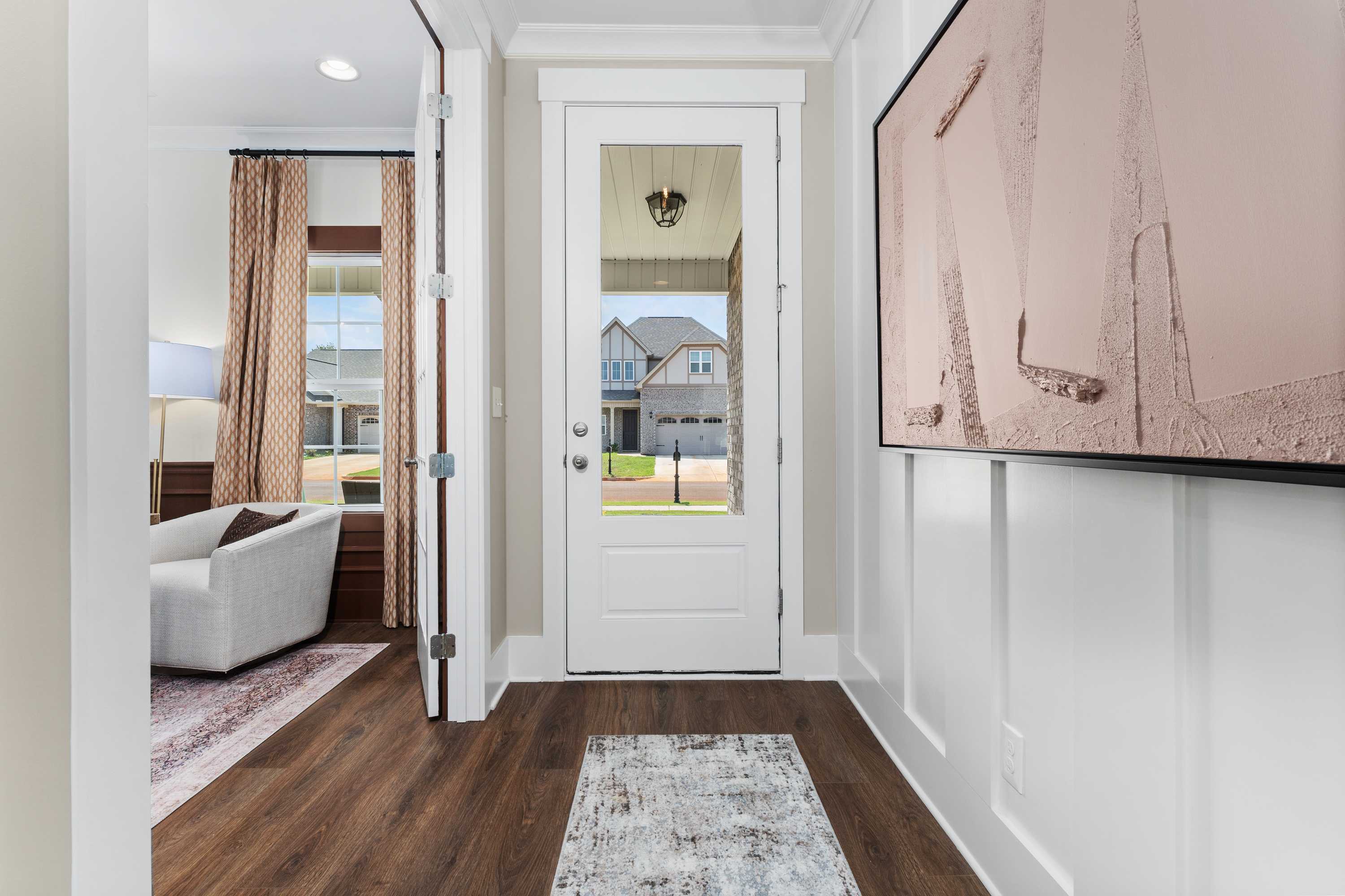 Spacious entryway at Ricketts Farm in Athens Alabama with hardwood floors white glass door cozy beige sofa and abstract wall art