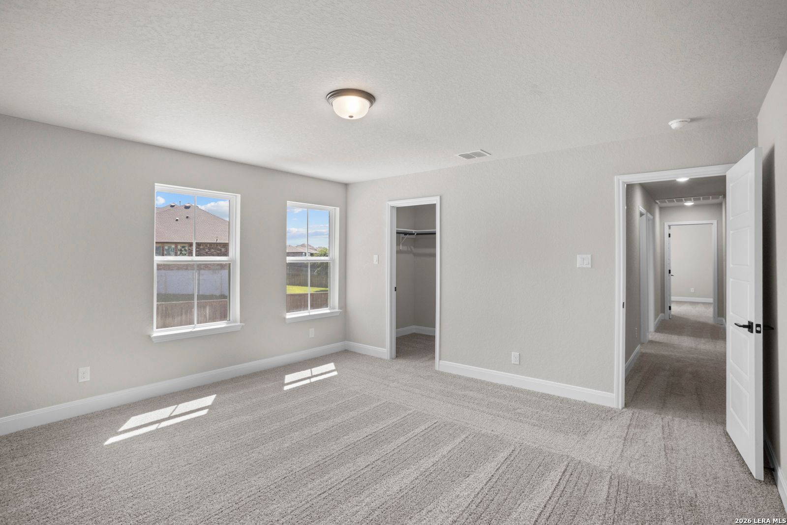 Spacious bedroom with neutral carpet, walk-in closet, and natural light in The Jennings G floor plan at Ladera, San Antonio.