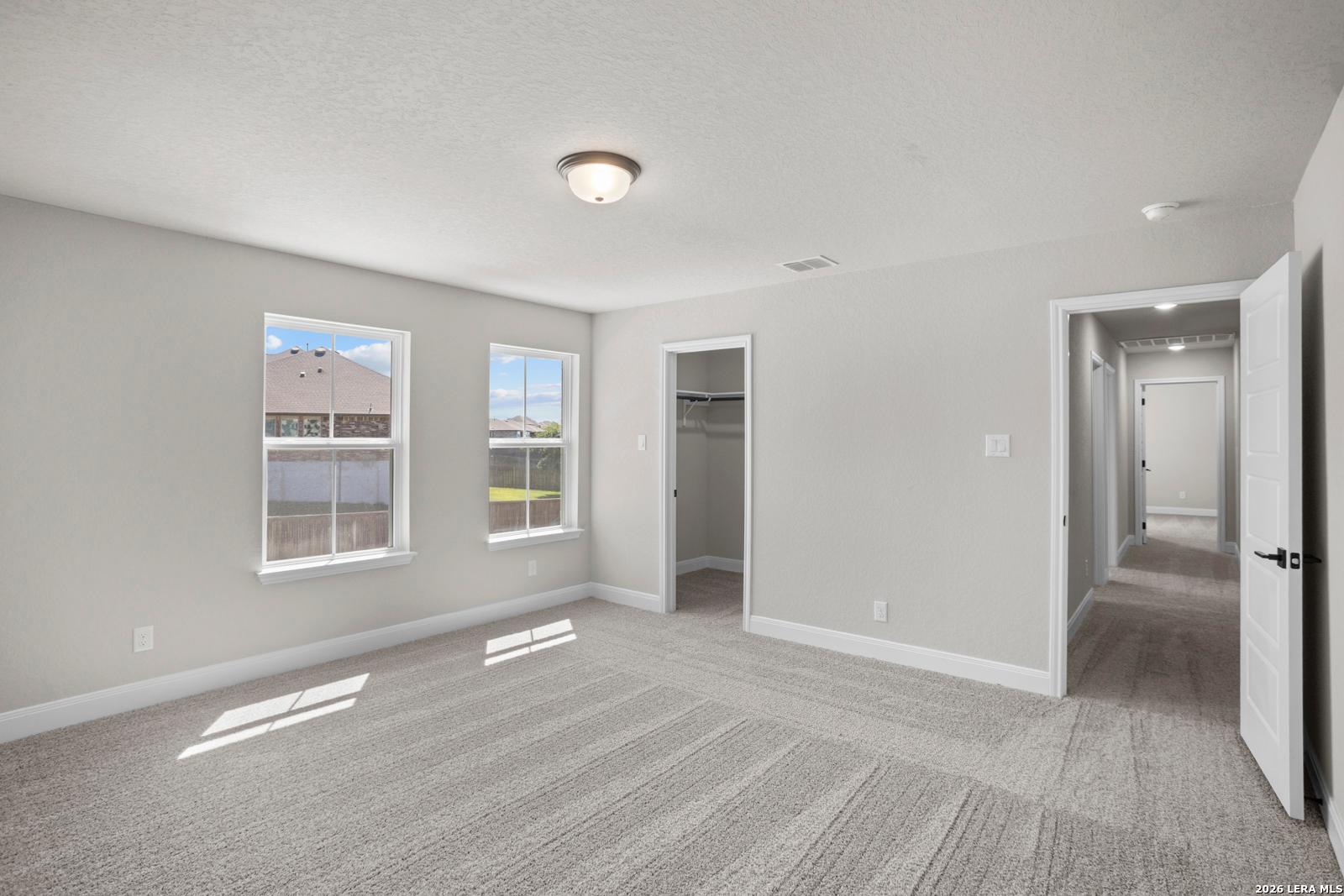Spacious bedroom with neutral carpet, walk-in closet, and natural light in The Jennings G floor plan at Ladera, San Antonio.