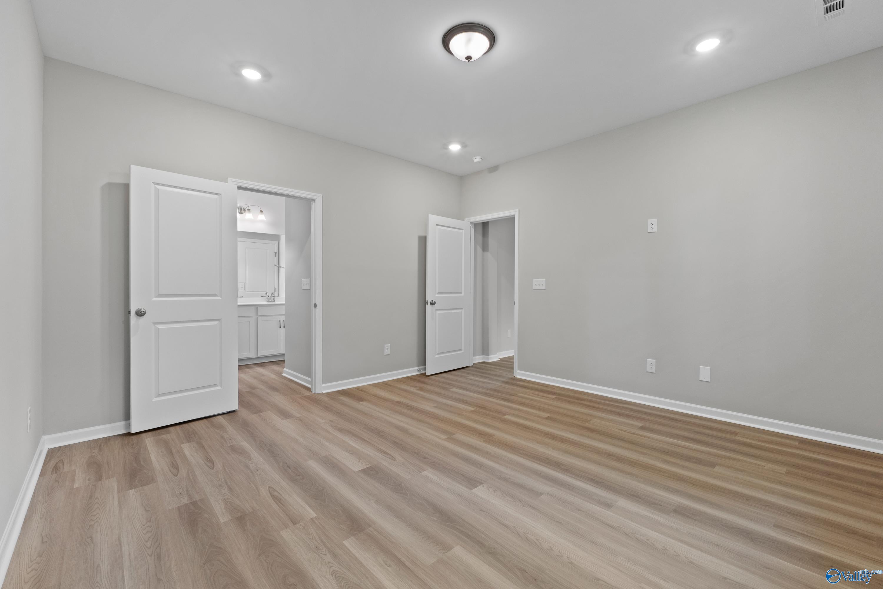 Spacious master bedroom with en-suite bath, hardwood floors, and gray walls in Davidson Homes Polaris, Fayetteville, TN