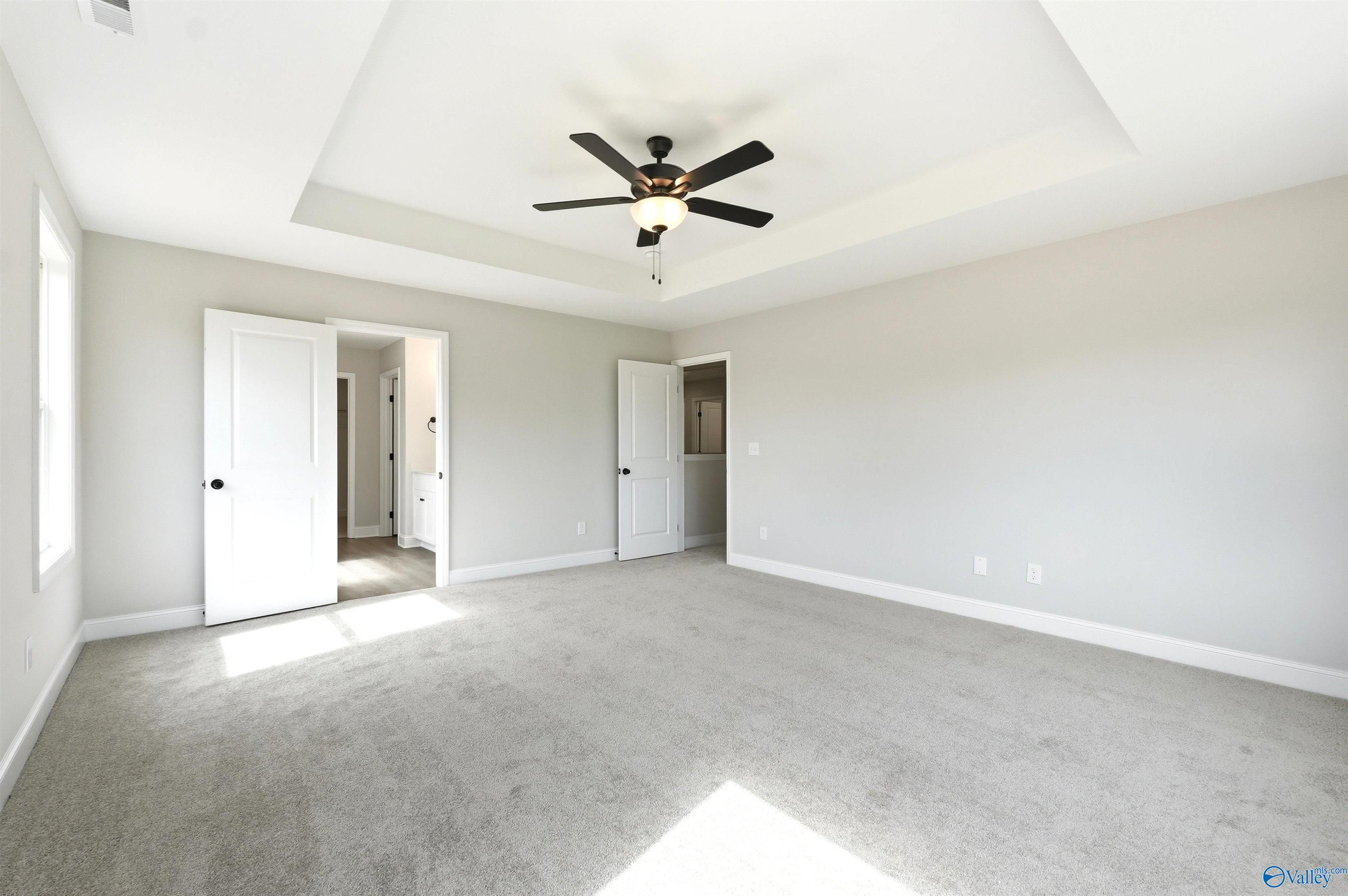 Spacious primary bedroom with tray ceiling and ceiling fan in The Chelsea D floor plan at Berry Cove, New Market, Alabama.