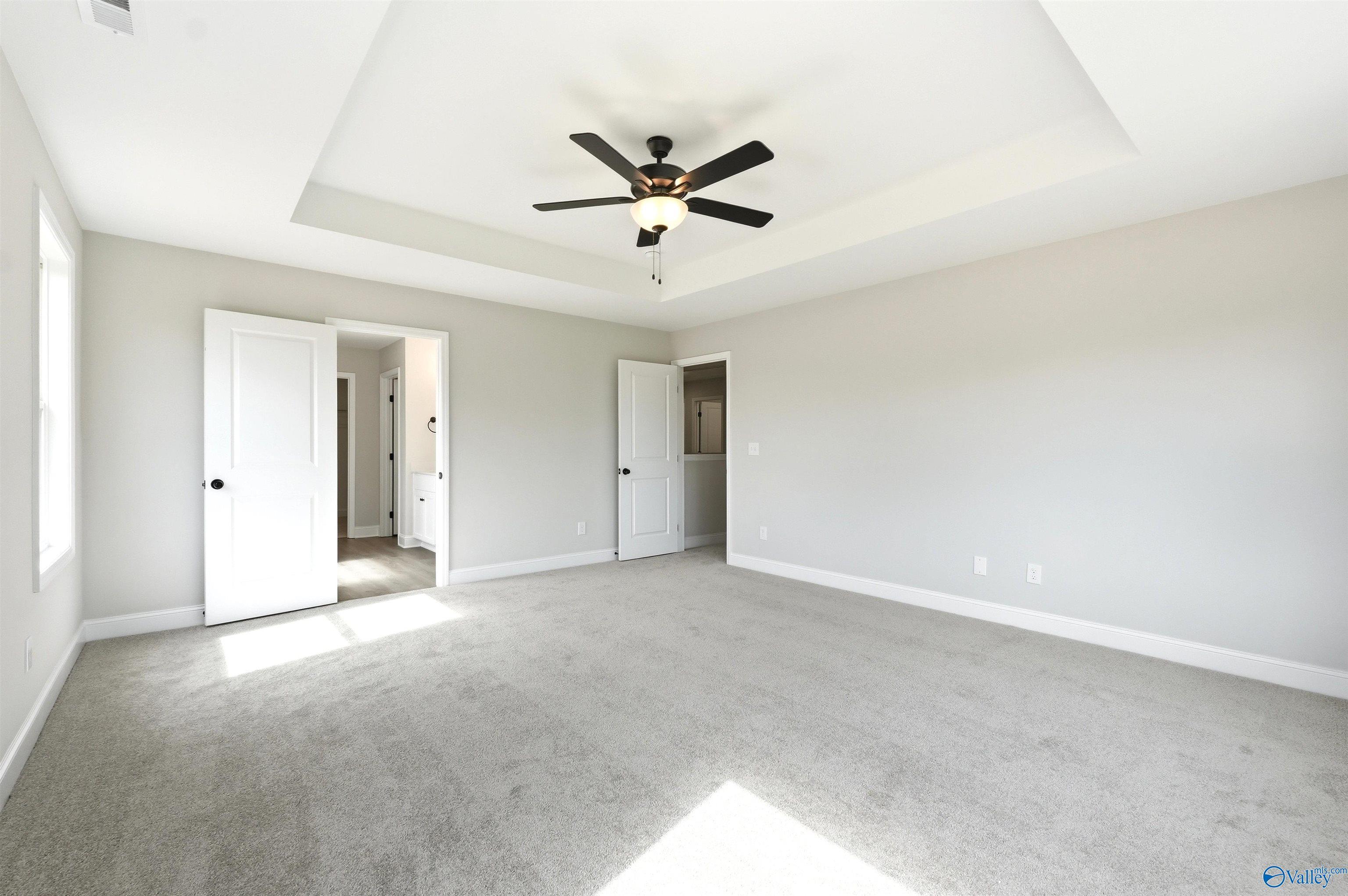 Spacious primary bedroom with tray ceiling and ceiling fan in The Chelsea D floor plan at Berry Cove, New Market, Alabama.