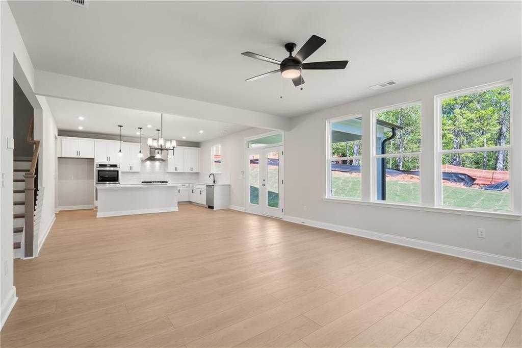 Open-concept kitchen and living area with white cabinets, island, hardwood floors, and backyard views in The Hickory B, Buford, GA