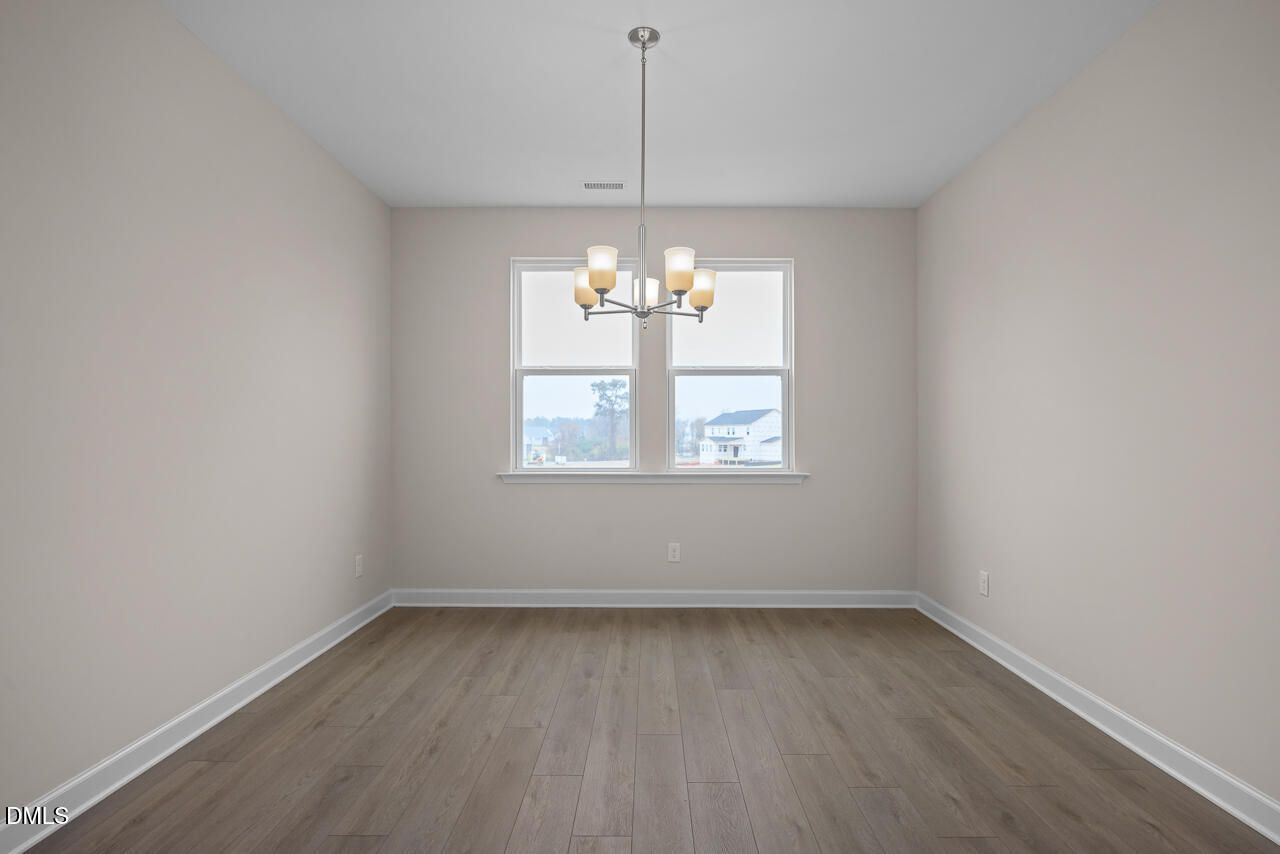 Formal dining room with hardwood floors, beige walls, modern chandelier, and large windows in Davidson Homes The Cypress D II, Angier, NC