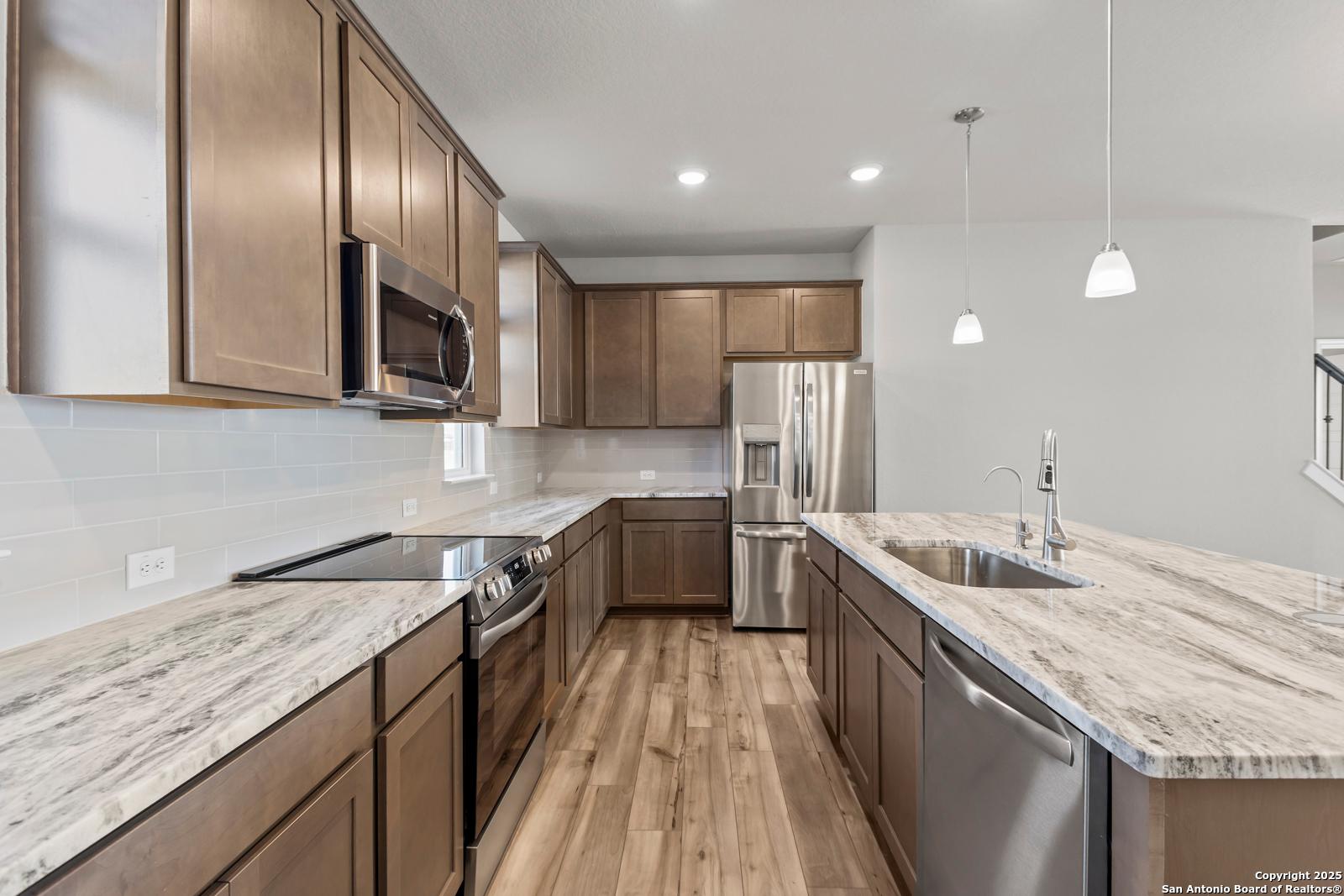 Open-concept kitchen with shaker cabinets, veined quartz countertops, stainless appliances in The Collin B by Davidson Homes, Seguin, Texas