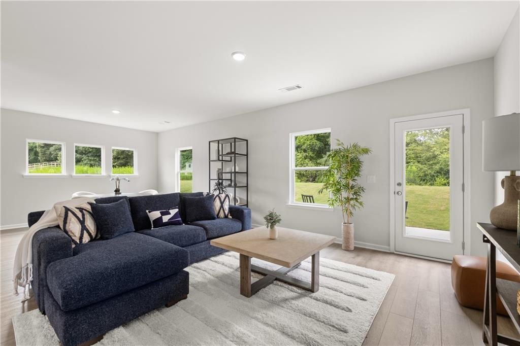 Bright, open-concept living room with navy sectional in The Sinclair B floor plan at Cedar Farms in Winder, Georgia.
