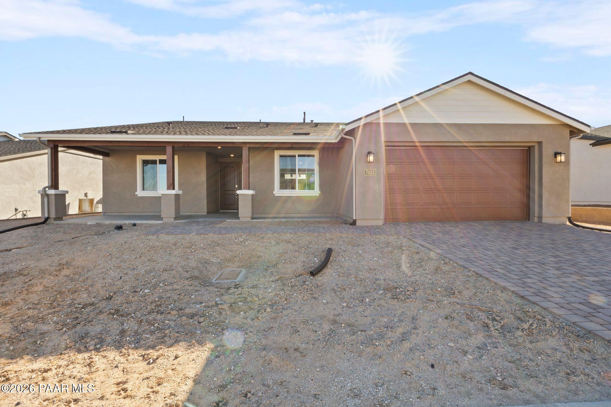 Tan single-story home with 3-car garage, paver driveway, and covered entry in sunny Westwood, Prescott, Arizona