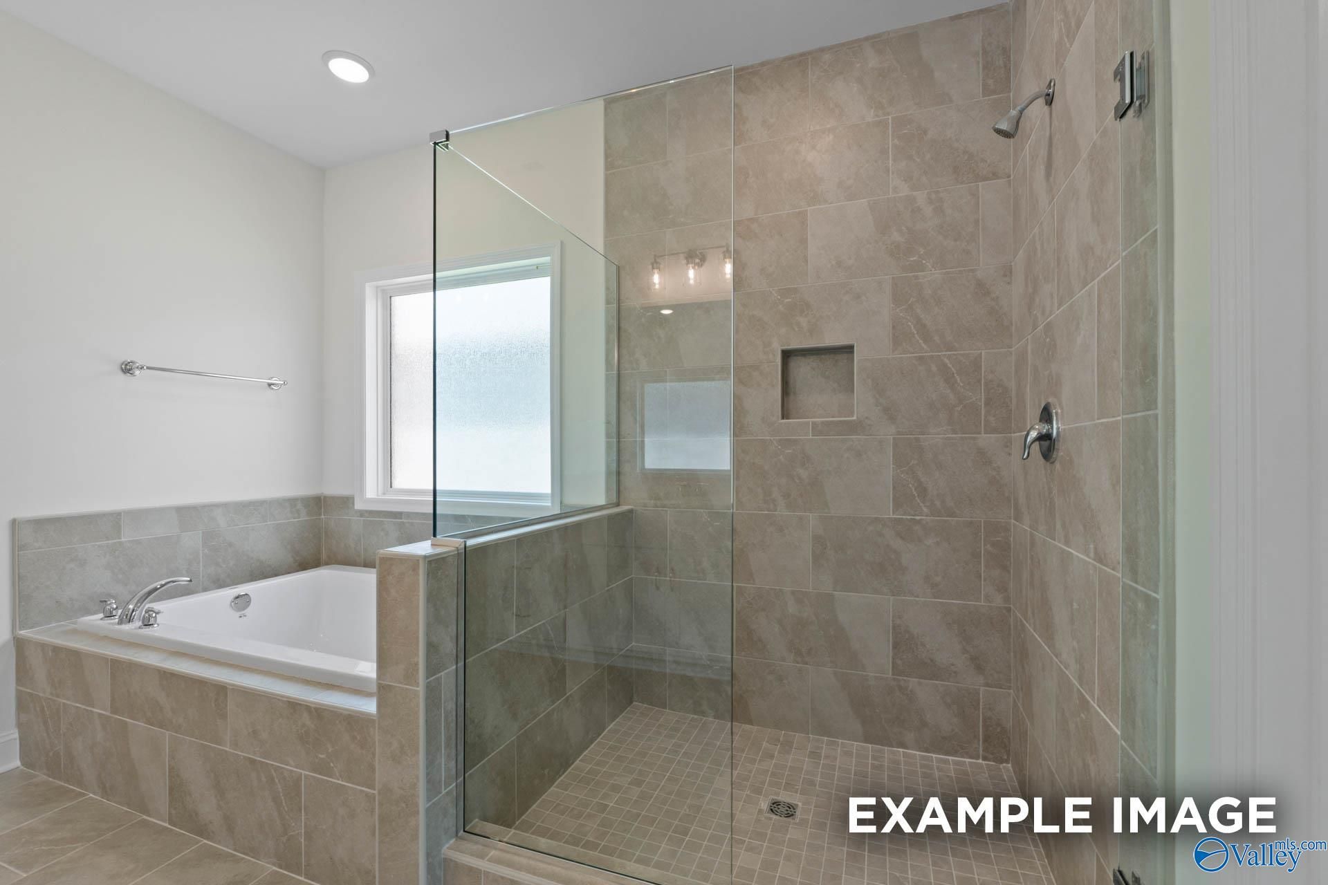 Elegant master bathroom with frameless glass shower, soaking tub, and tiled accents in Davidson Homes The Oxford, Huntsville AL