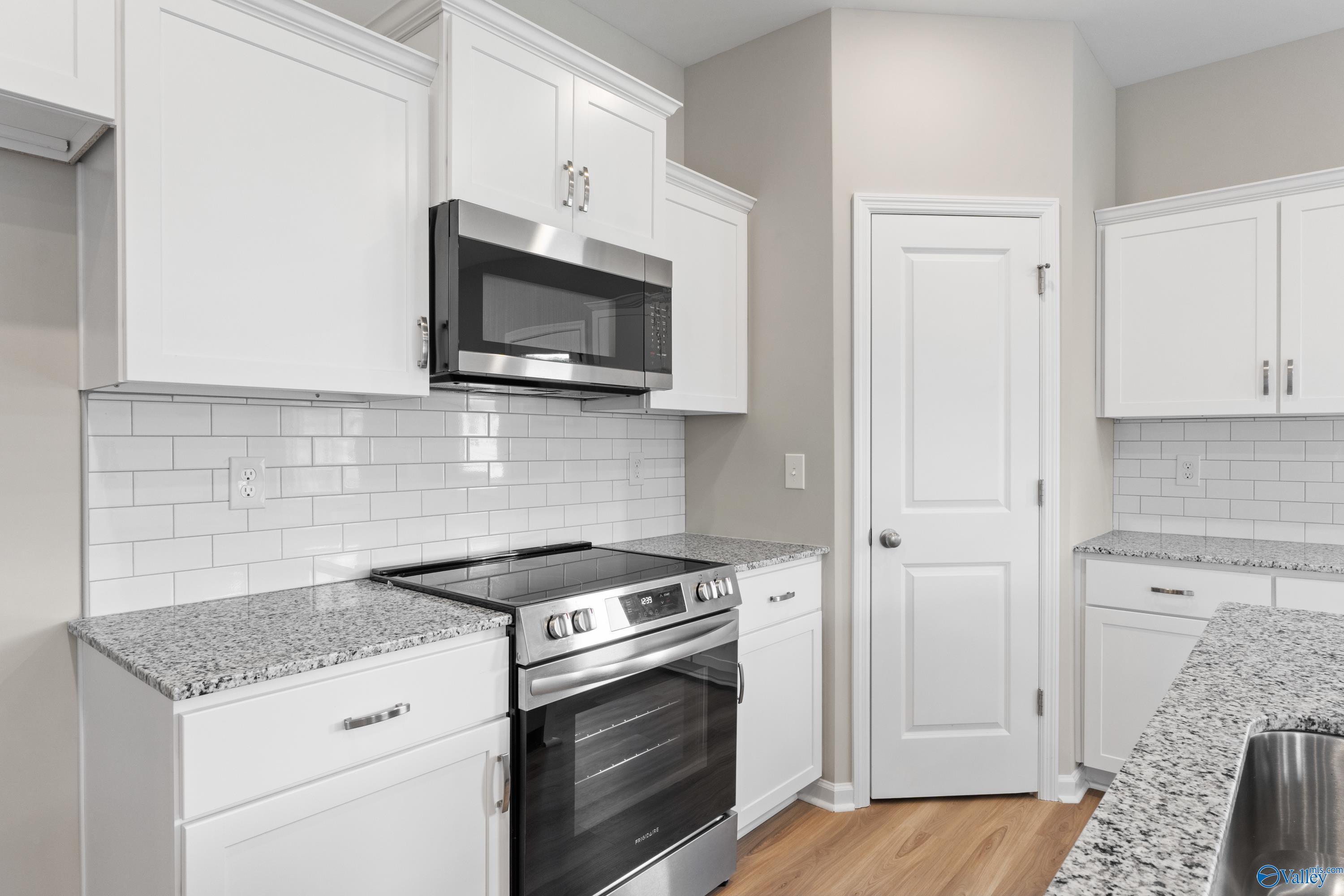 Modern kitchen featuring white shaker cabinets, granite countertops, subway tile backsplash, and stainless appliances in Davidson Homes The Augusta, Madison, AL