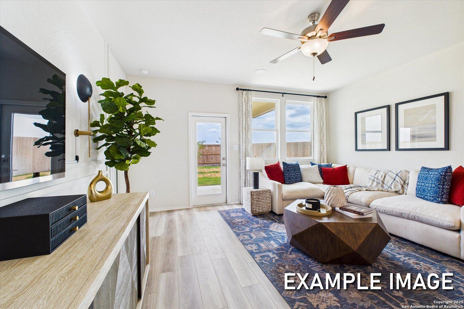 Cozy living room with white sectional sofa, mounted TV, fiddle leaf plant, and sliding doors to backyard in Davidson Homes The Brazos C, Agave San Antonio Texas
