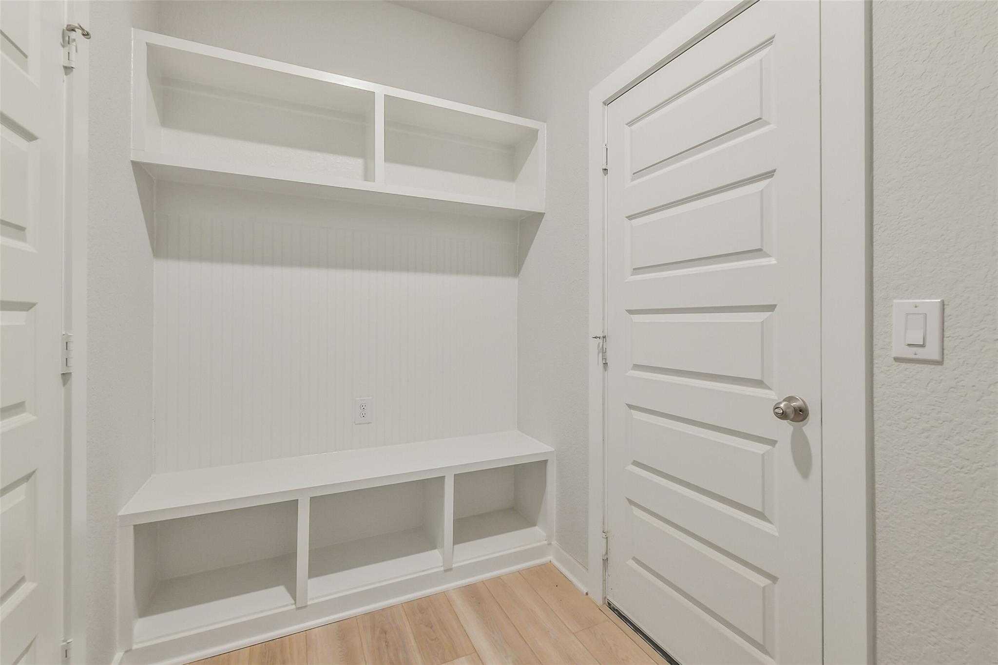 White built-in mudroom lockers with benches and open shelves in Davidson Homes The Rio Grande H, Magnolia, Texas