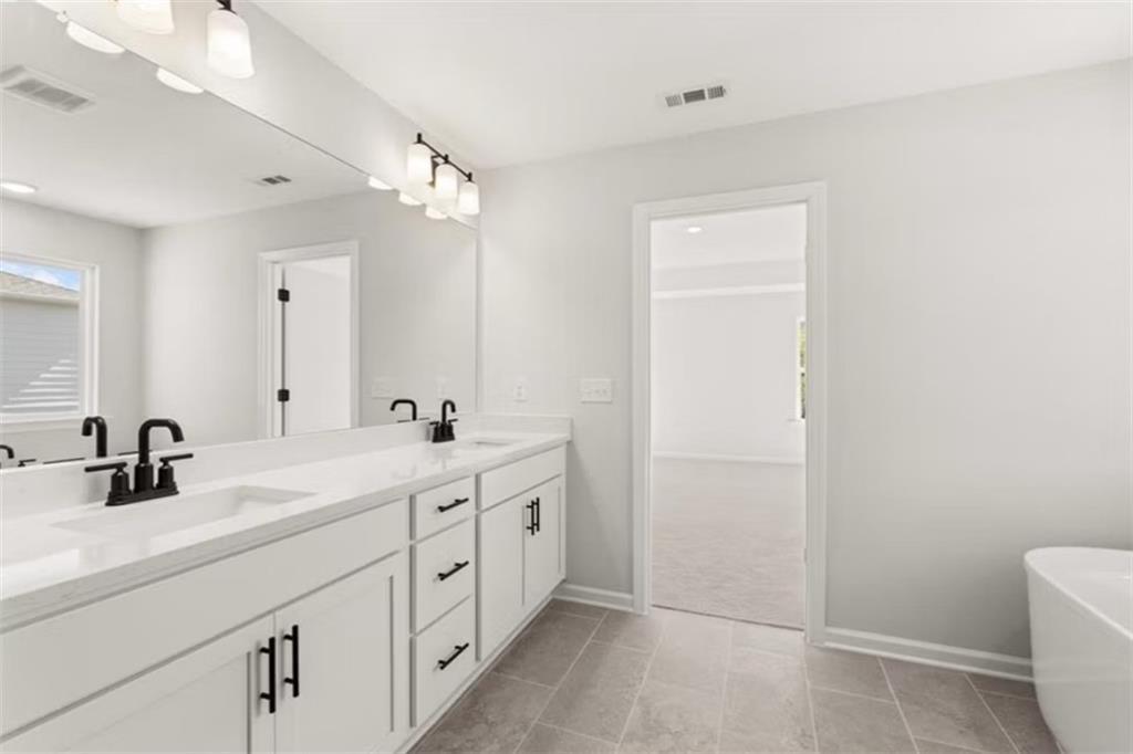Modern master bathroom with double white quartz vanity, black faucets, freestanding tub in Davidson Homes The Hickory B, Winder, Georgia
