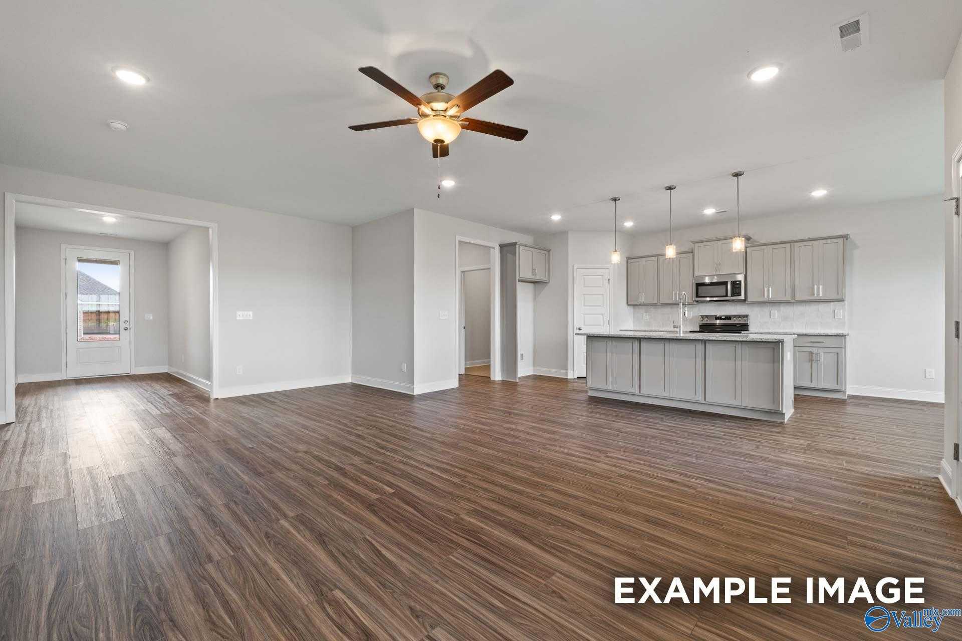 Modern open-concept kitchen and living area with gray cabinets, island, stainless appliances, hardwood floors in Davidson Homes The Montgomery, Athens AL