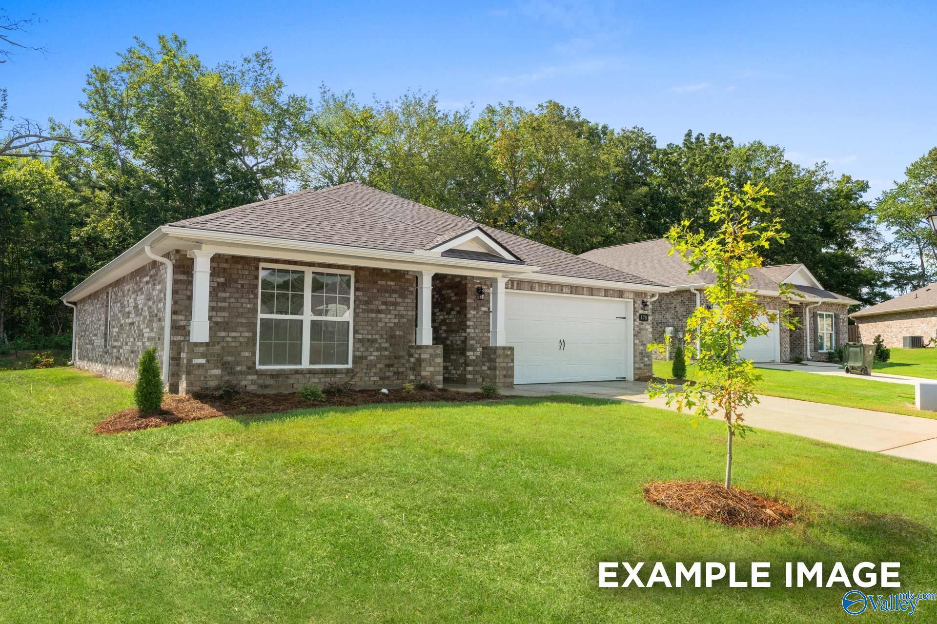 Brick single-story home with gabled roof, columned porch, and 2-car garage amid green lawn in Hazel Green, Alabama