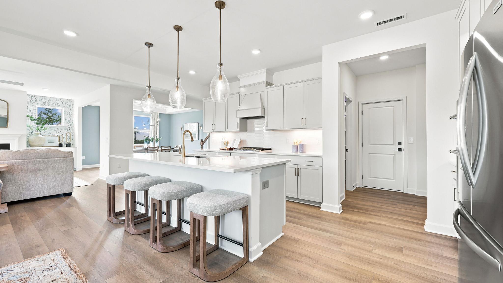 Modern kitchen in a Addison West home by Davidson Homes featuring white cabinets, stainless steel appliances, and island.