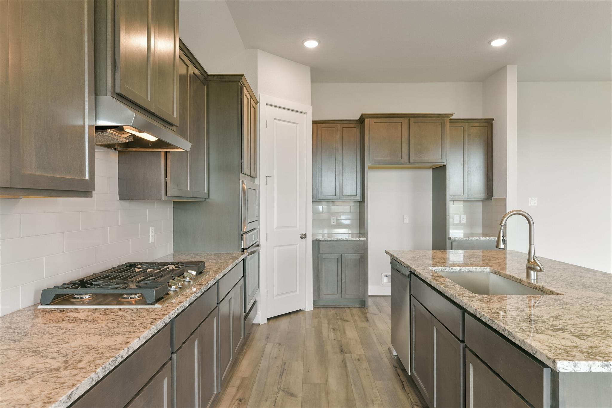 Modern kitchen featuring granite island, stainless appliances, dark shaker cabinets in Davidson Homes The Edward A, Lago Mar, Texas City