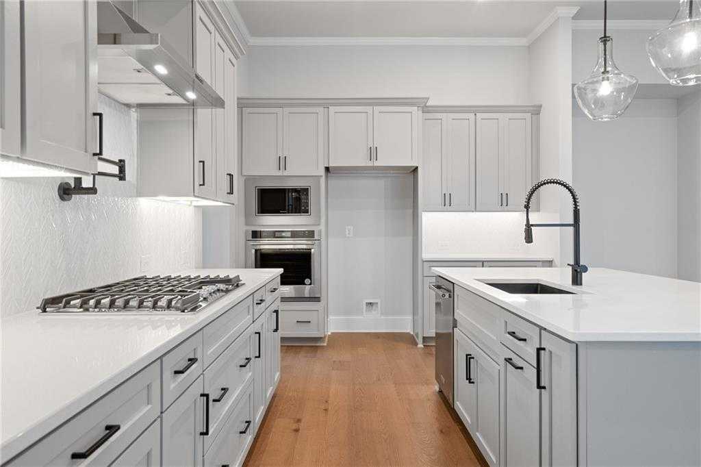 Modern white shaker kitchen with quartz island, stainless appliances, gas range in Davidson Homes The Seaside B, Woodstock, GA