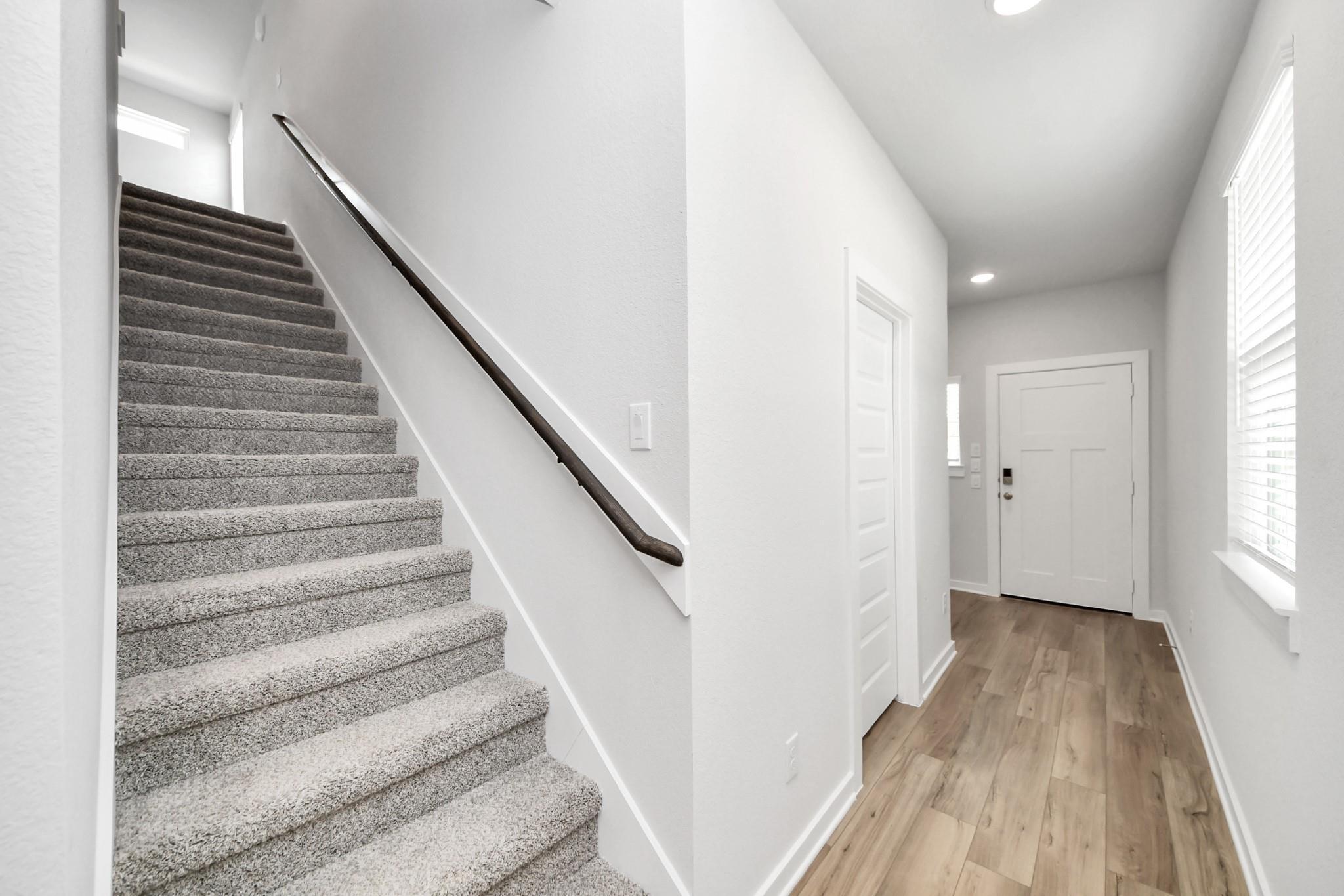Bright entryway with wood-look flooring and carpeted staircase in The Sabine E floor plan by Davidson Homes in Cleveland.