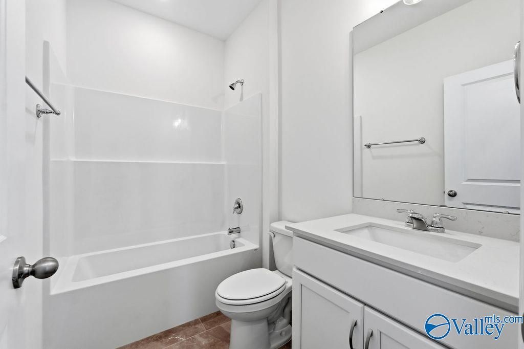 Bright white secondary bathroom with tub-shower combo, vanity sink, and mirror in Davidson Homes The Montgomery, Hartselle, AL