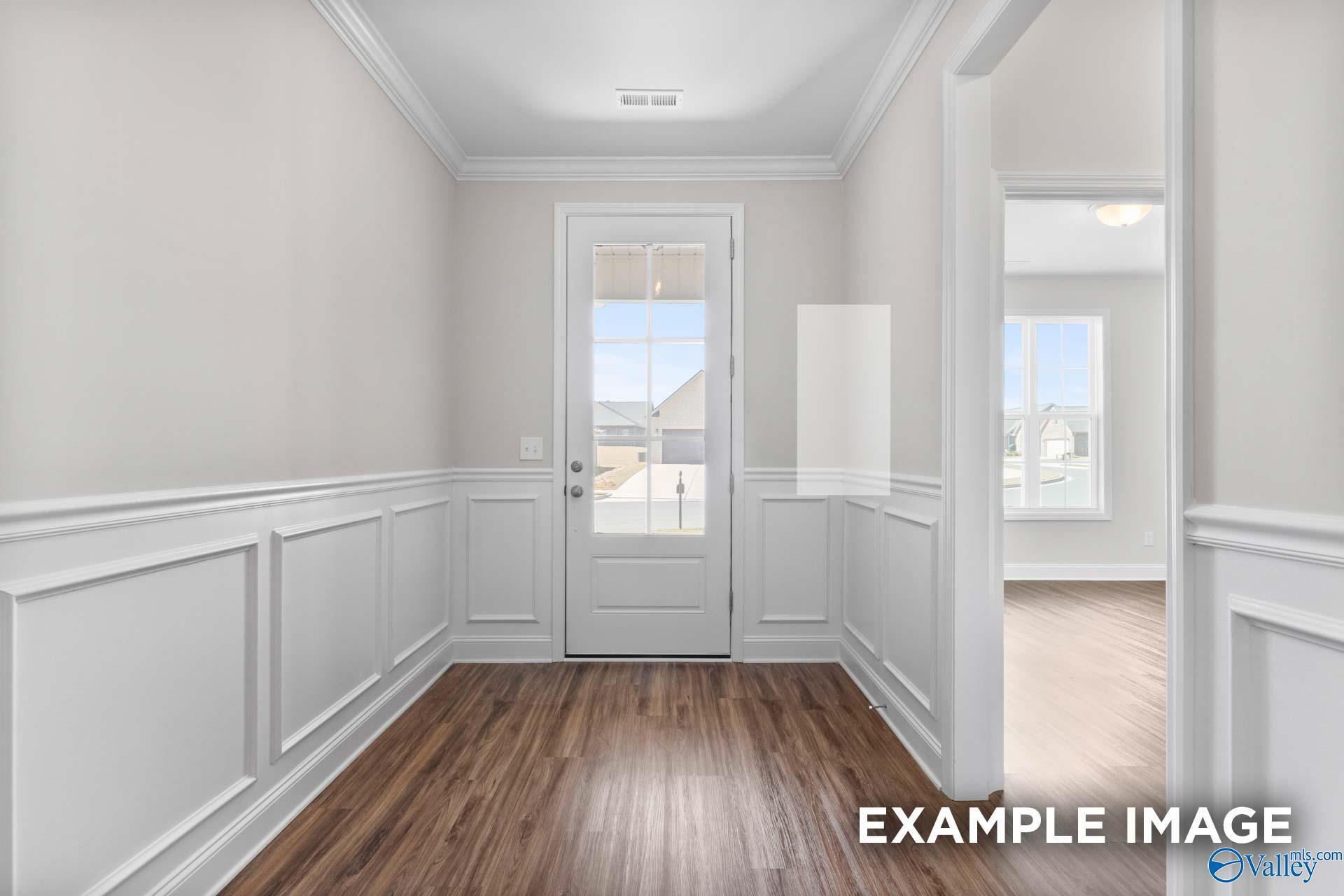 Elegant entry foyer with white wainscoting, hardwood floors, and glass-paneled door in Davidson Homes The Montgomery C, Harvest, Alabama