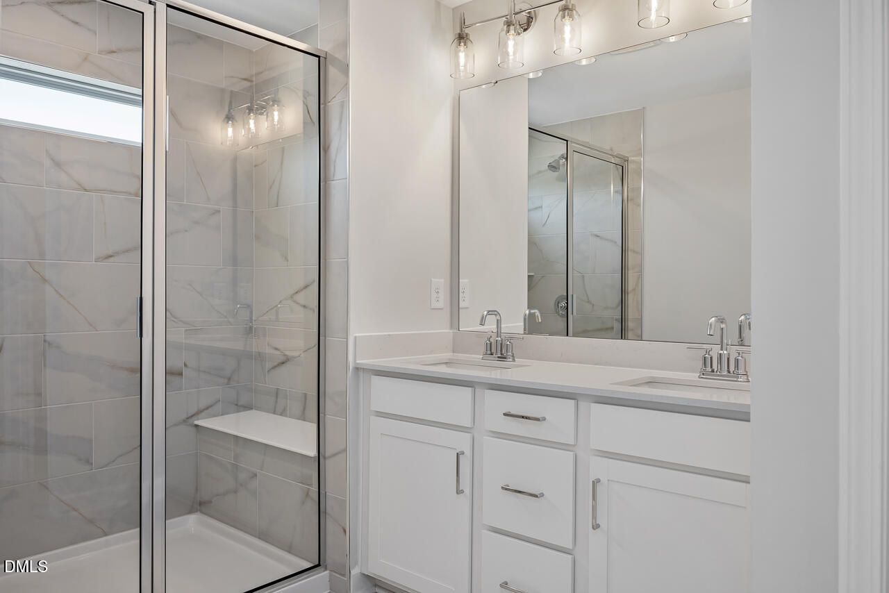 Modern bathroom with marble-tile walk-in shower and dual-sink vanity in The Mitchell at Camden Park, Knightdale, NC.