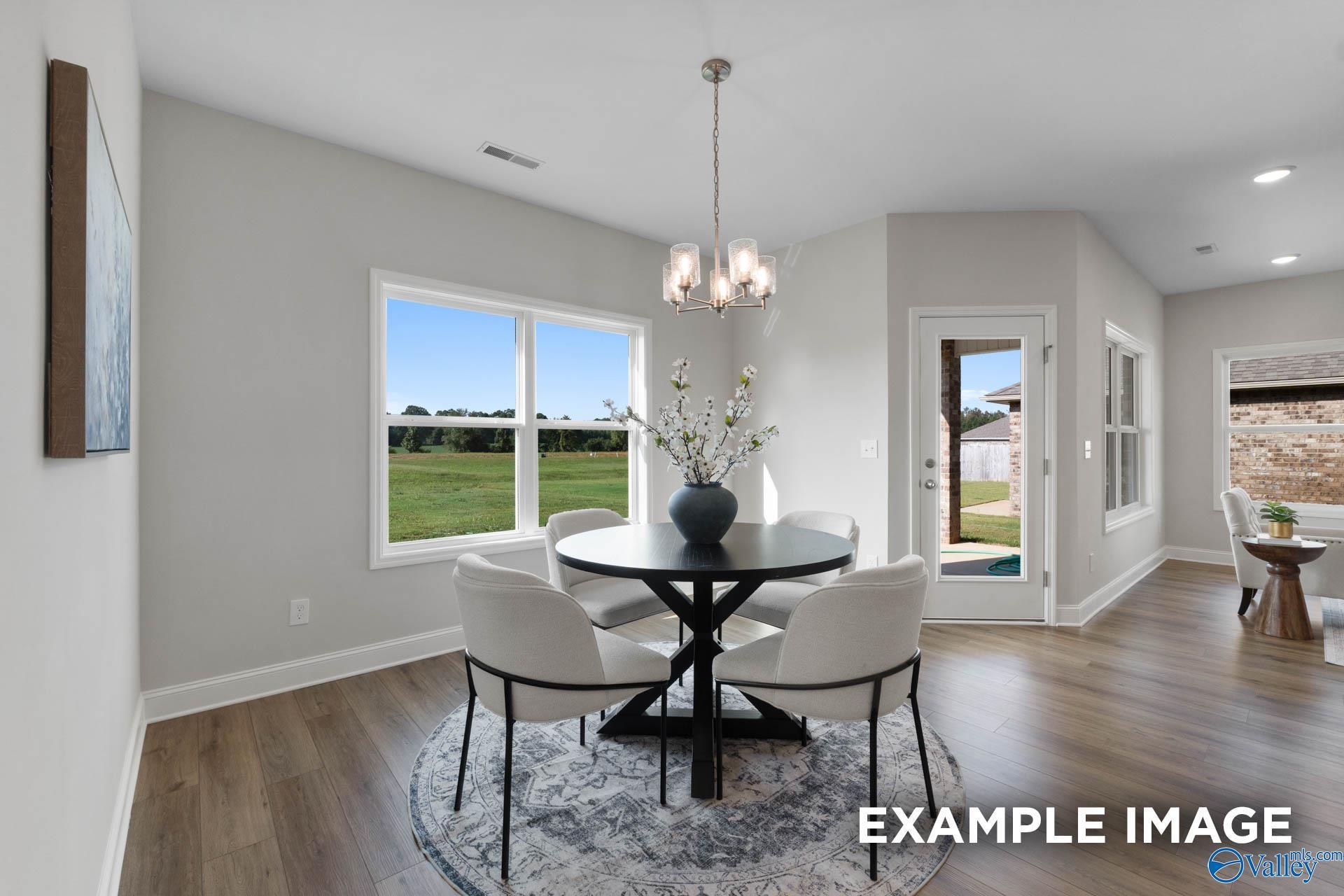 Bright breakfast nook with round table, modern chairs, and backyard views in The Franklin C home at Heritage Lakes.