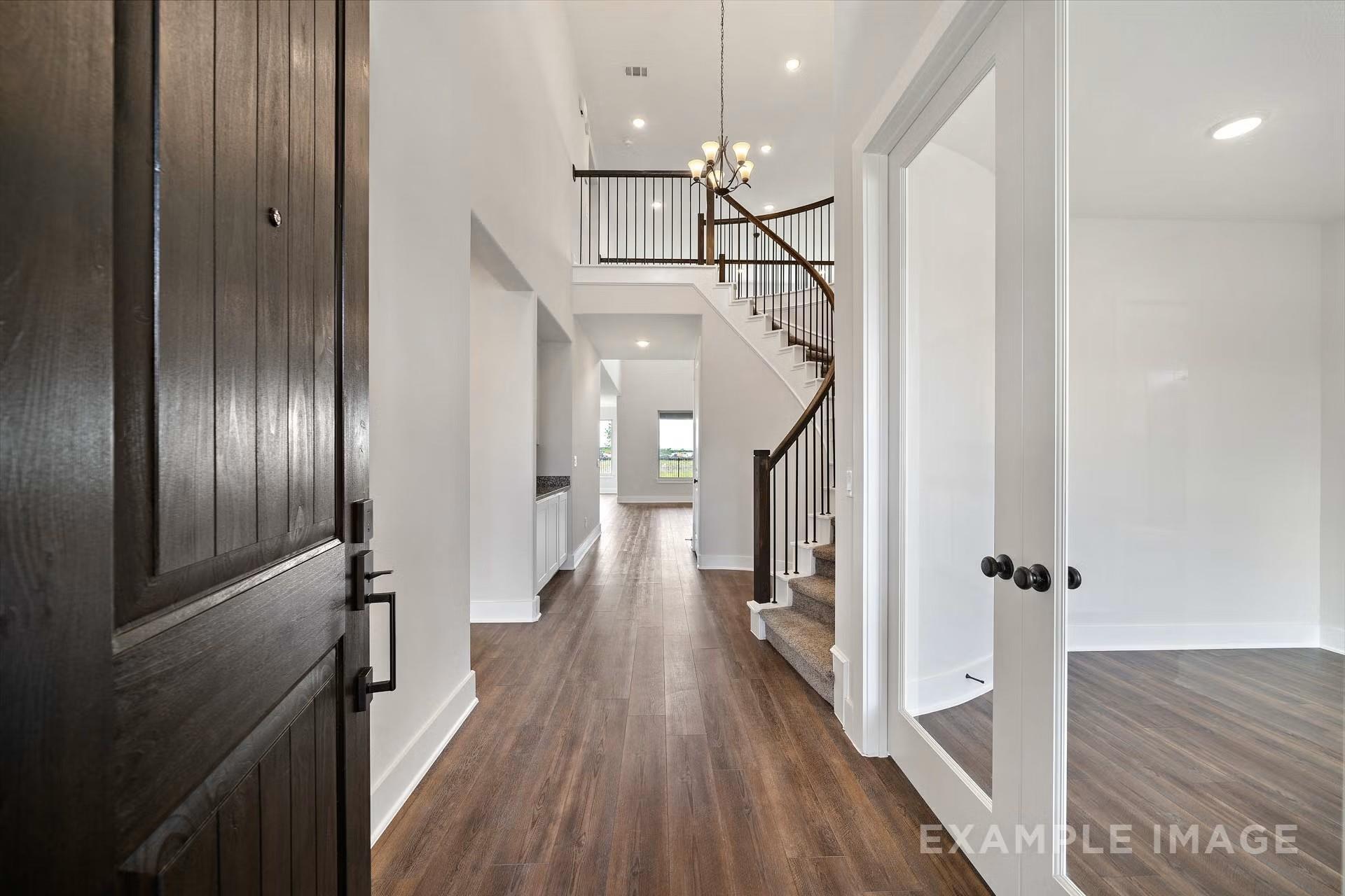 Grand entry foyer with dark wood staircase, chandelier, and hardwood floors in Davidson Homes The Victoria A, Lago Mar, Texas City
