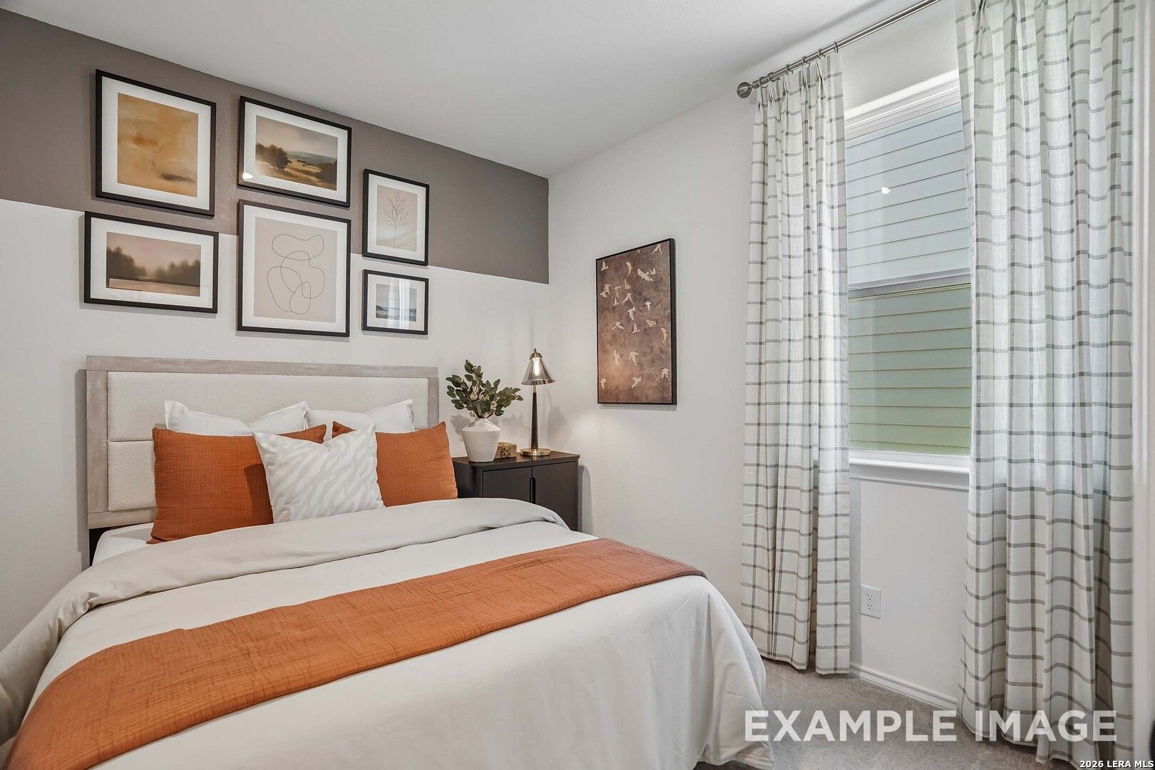 Cozy bedroom with gallery wall, upholstered headboard, and orange accents in Davidson Homes The Pinecrest E, Fairway Crossing, Converse Texas