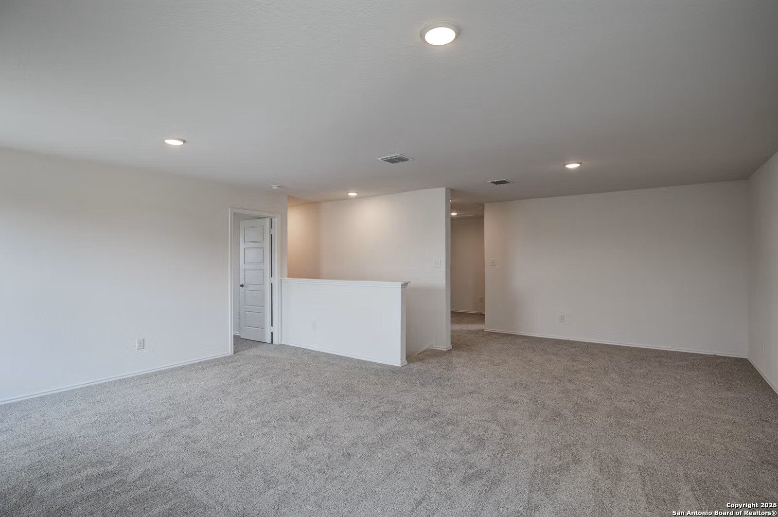Spacious upstairs hallway with beige carpet, white walls, recessed lights, and balcony overlook in Davidson Homes The Douglas B, Seguin, Texas
