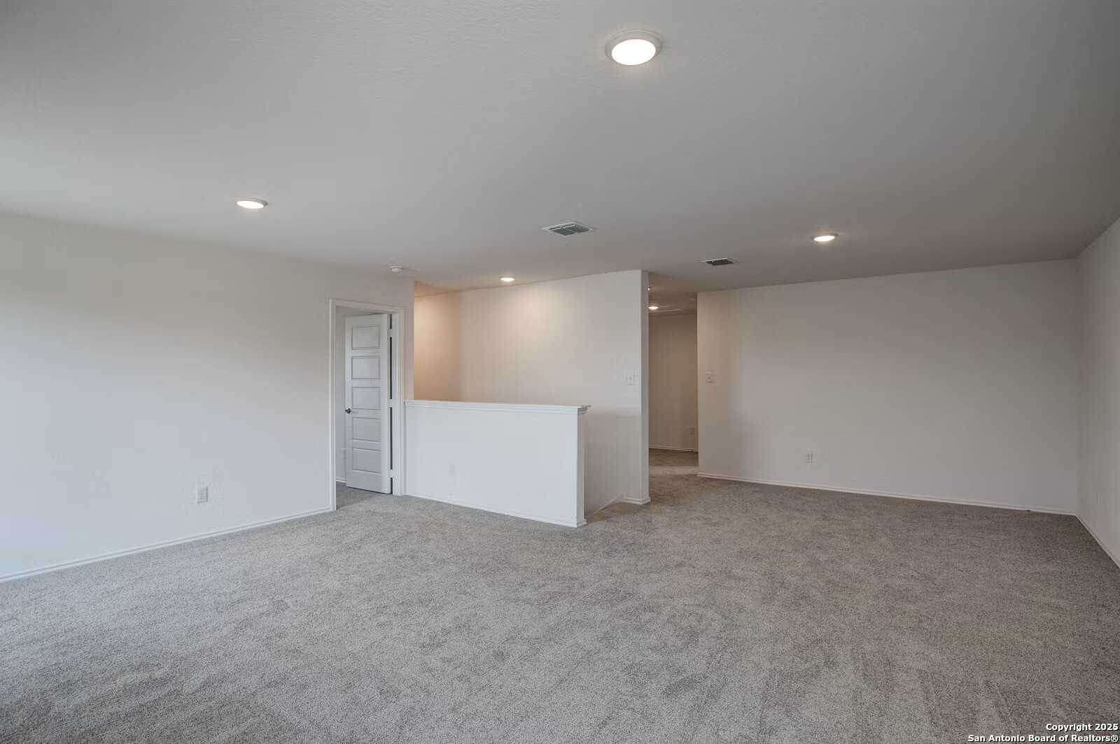 Spacious upstairs hallway with beige carpet, white walls, recessed lights, and balcony overlook in Davidson Homes The Douglas B, Seguin, Texas