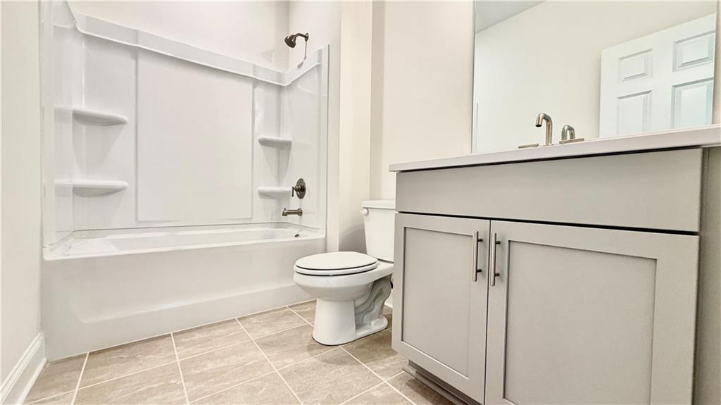 Modern bathroom with white tub-shower combo and gray vanity in The Hickory C floor plan at Wehunt Meadows, Hoschton, GA.