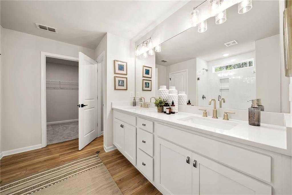 Modern master bathroom featuring double white vanity, frameless mirror, walk-in closet, and glass shower in Davidson Homes The Hickory B, Dallas, Georgia