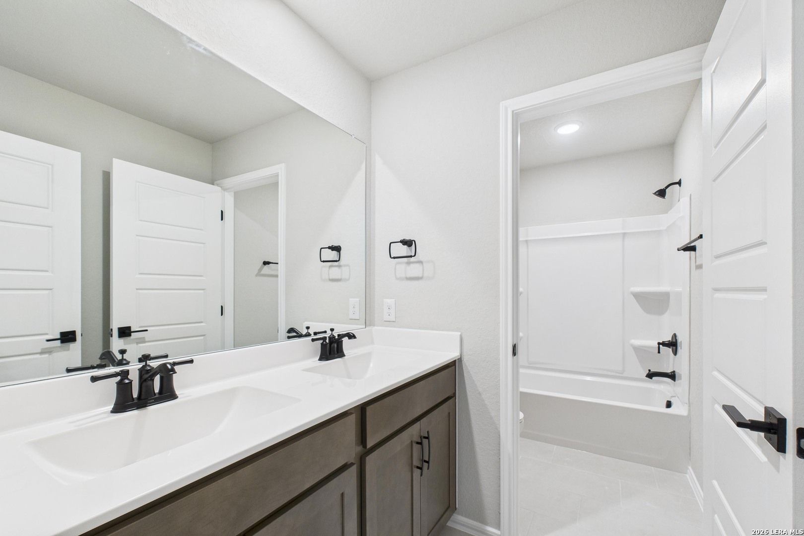 Modern double vanity bathroom with soaking tub, frameless shower and white tile in Davidson Homes The Douglas E, San Antonio