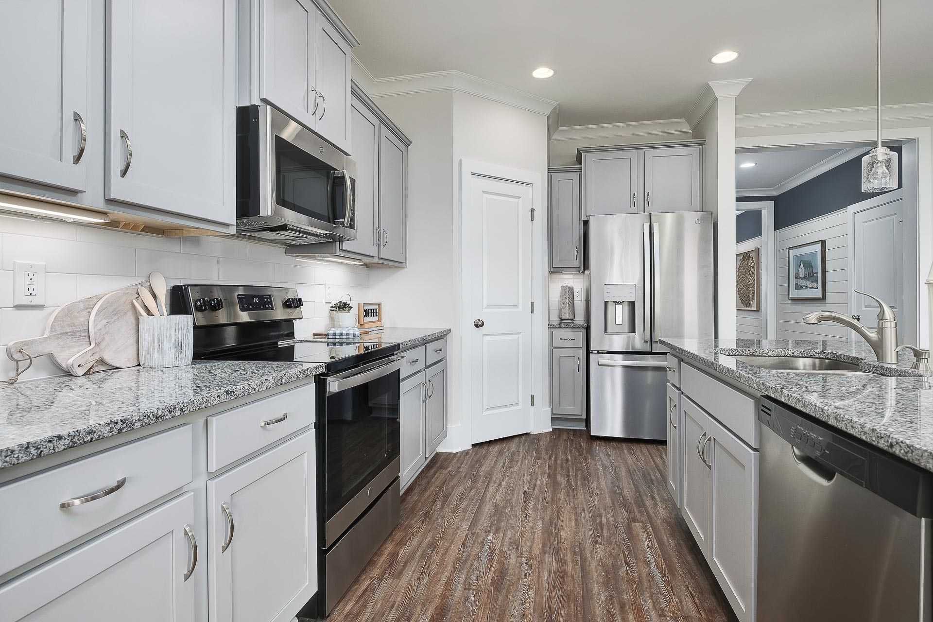 Modern kitchen in The Everett C with white shaker cabinets, granite island, stainless steel appliances, and open layout