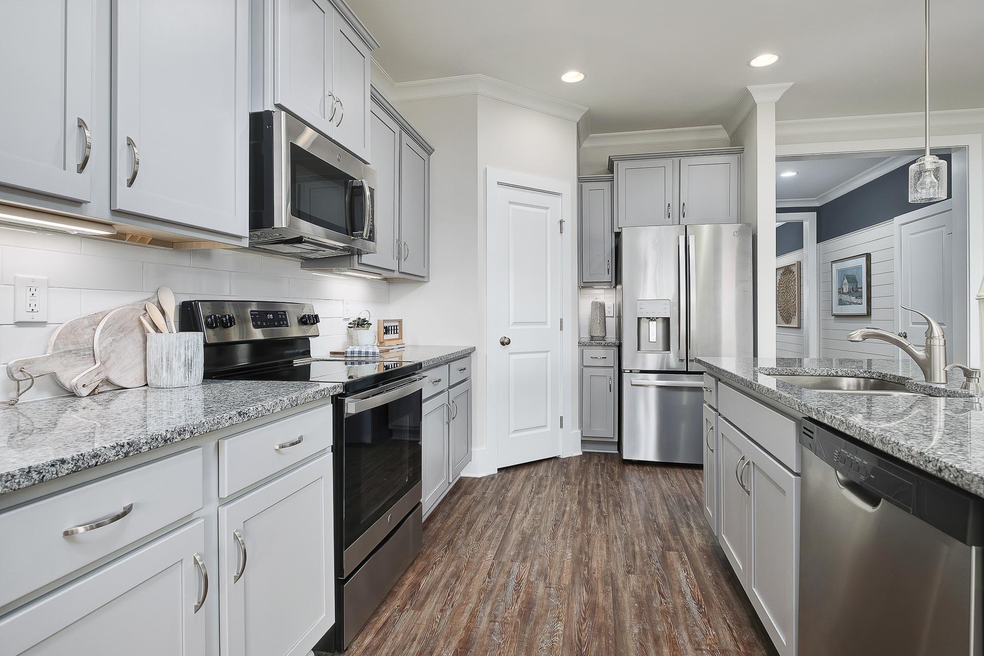 Spacious kitchen in The Everett Davidson Homes with white shaker cabinets, stainless steel appliances, and granite island