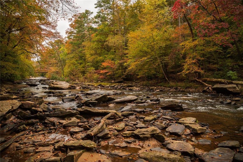 Serene autumn stream with vibrant fall foliage, rocky banks, and flowing water in The Village at Shallowford, Kennesaw, Georgia